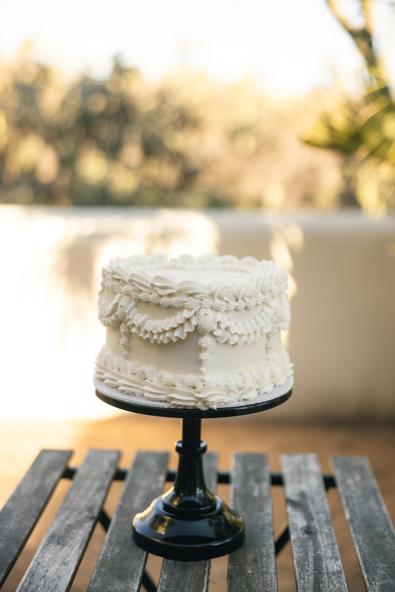 Vintage heart cake on a black cake stand, featuring intricate piping and classic wedding charm, a timeless detail for Tucson elopement inspiration rocky mountain bride.
