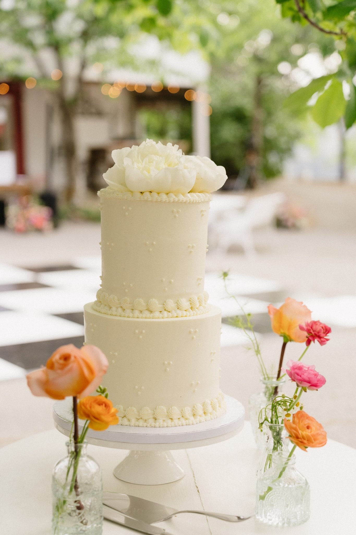 A two tiered cake with a smooth white finish, pearl and frosted dots for a darling cake design for a God’s Mountain Estate summer wedding