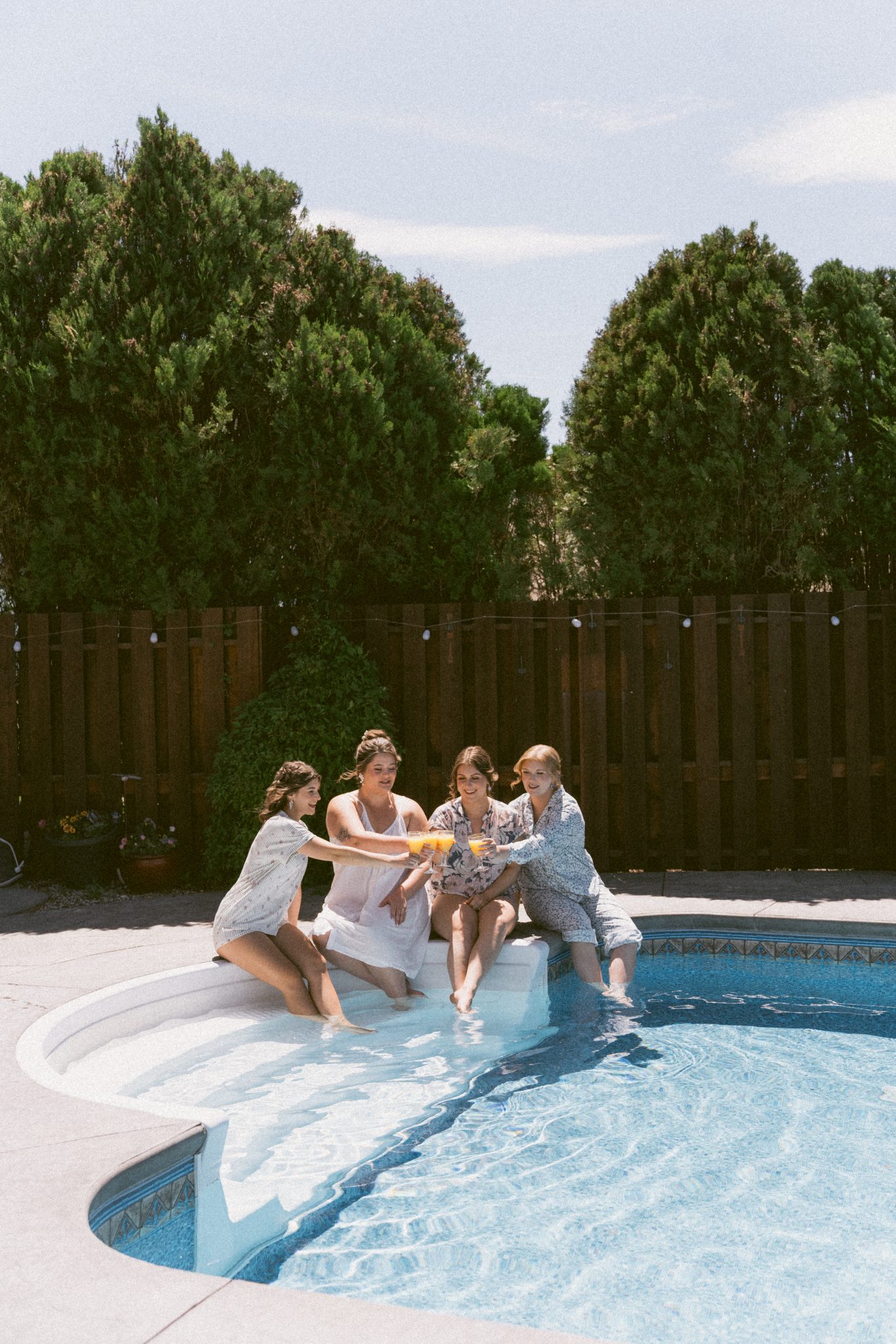 Bride and bridesmaids enjoying a mimosa by the pool before a God’s Mountain Estate summer wedding