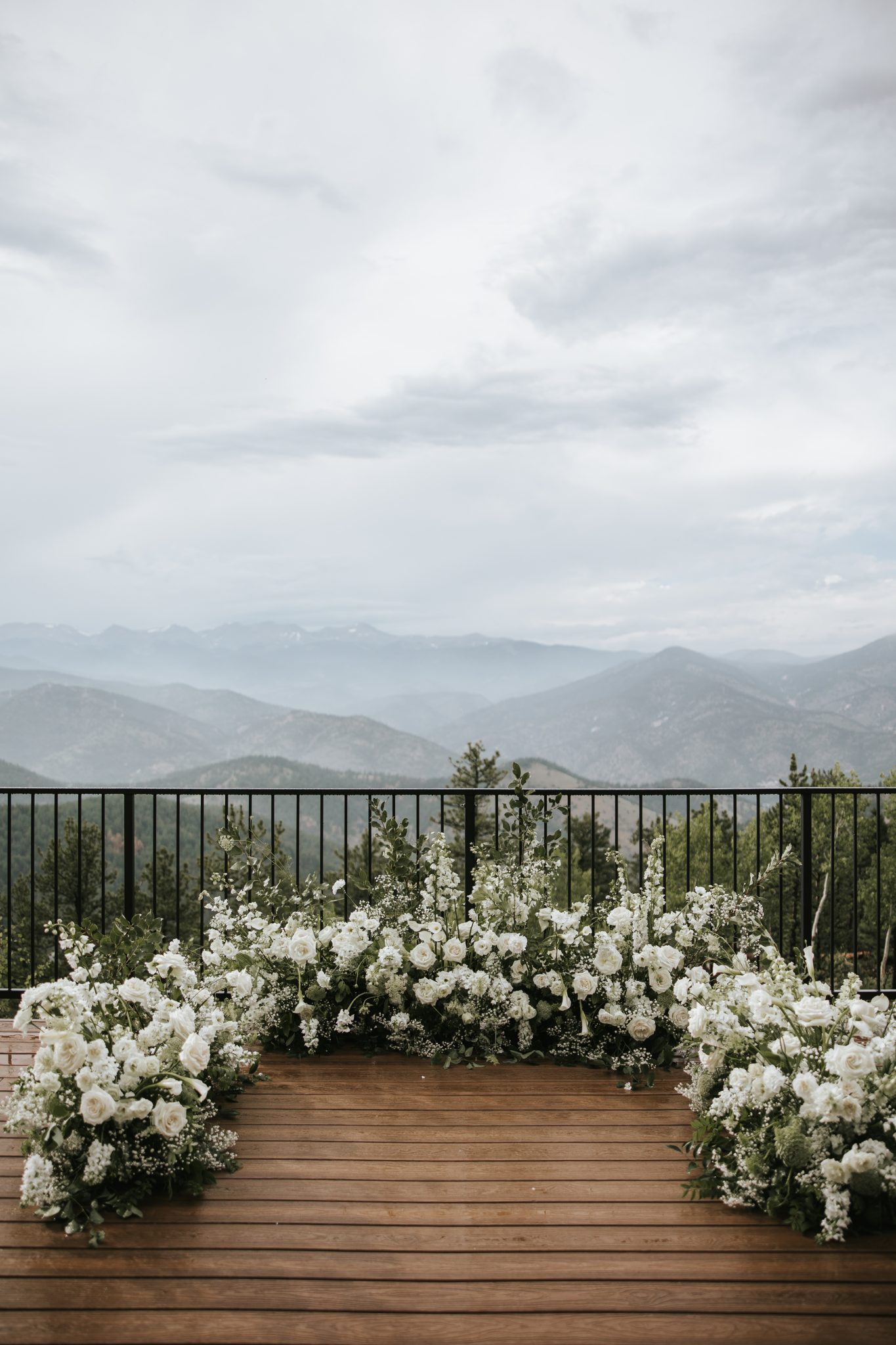 A breathtaking mountain ceremony setup with a floral-lined altar overlooking the Rockies, setting the scene for a North Start Gathering wedding in Idaho Springs Rocky Mountain Bride.