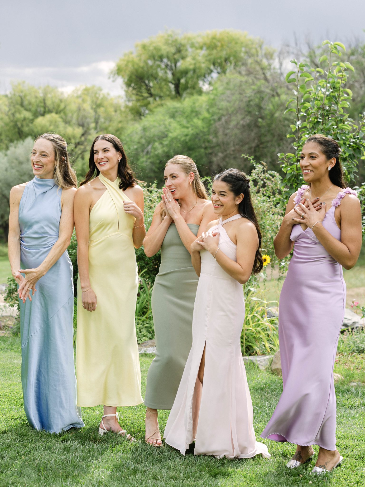 Bridesmaids in soft pastel dresses react with joy seeing the bride at a Private Property Tented Wedding in New Mexico