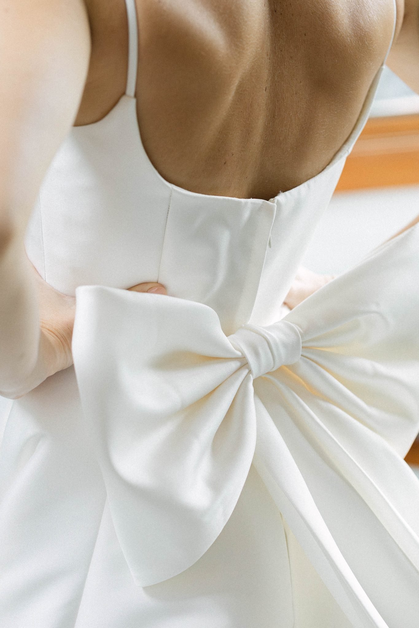 Close-up of a minimalist satin wedding gown with an oversized bow detail at a Private Property Tented Wedding in New Mexico.