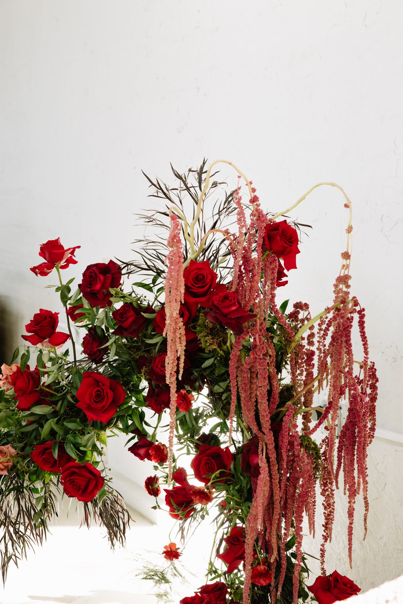 Detail of dramatic red rose and hanging amaranthus floral design for moody red wedding inspiration rocky mountain bride editorial.
