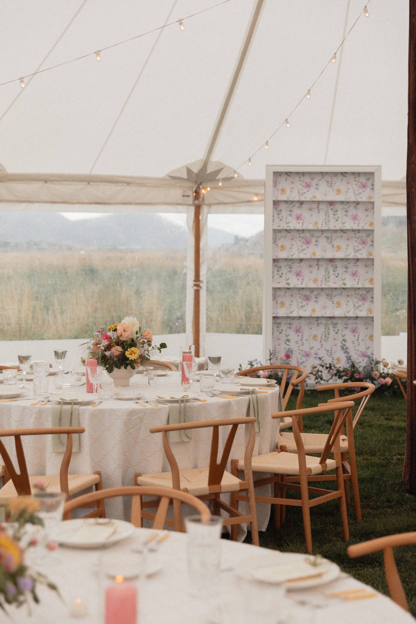 Tented reception with string lights and pastel floral arrangements at a pink and yellow Crested Butte wedding rocky mountain bride