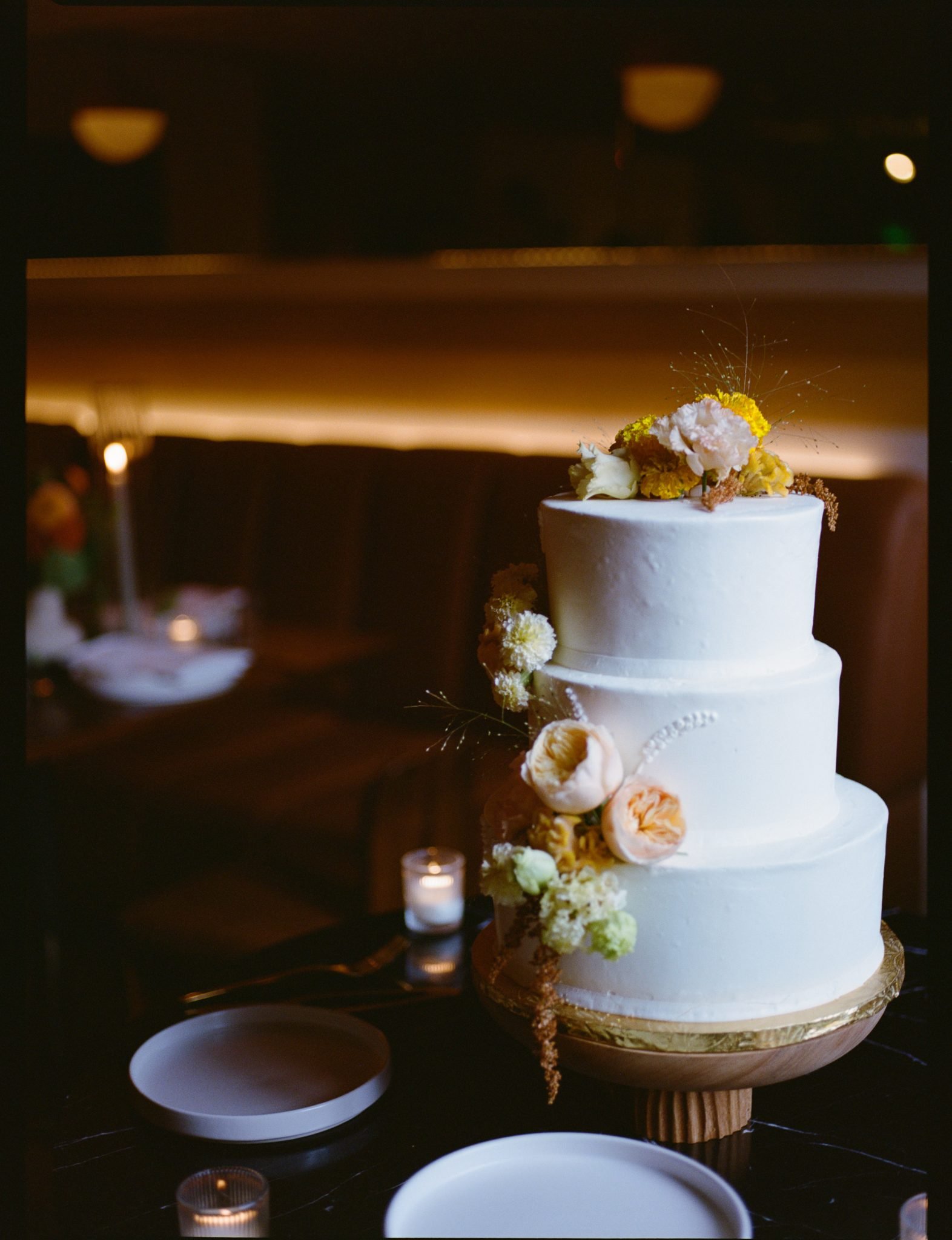 Elegant three-tiered cake decorated with soft florals at an A Frame Club Fall wedding rocky mountain bride reception.