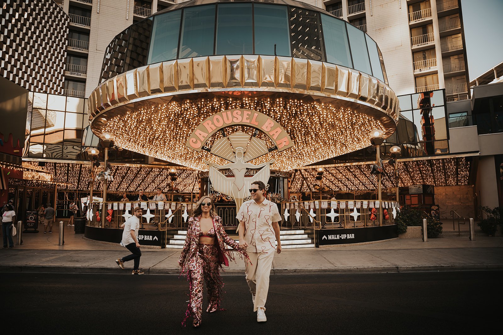 A stylish bride and groom walk hand in hand in front of the iconic Carousel Bar during their Shore Lodge Idaho wedding rocky mountain bride weekend.