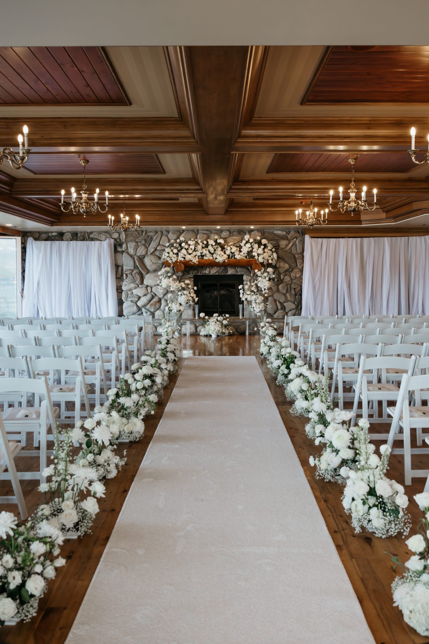 White floral ceremony setup with fireplace backdrop at Shore Lodge Idaho wedding rocky mountain bride event.