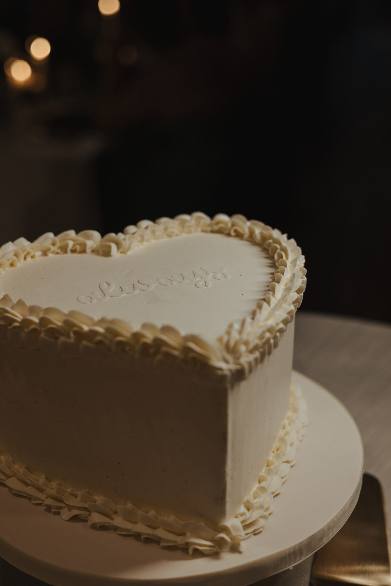 Minimalist heart-shaped white buttercream cake with piped details at The Permanent summer wedding in British Columbia rocky mountain bride dessert display.