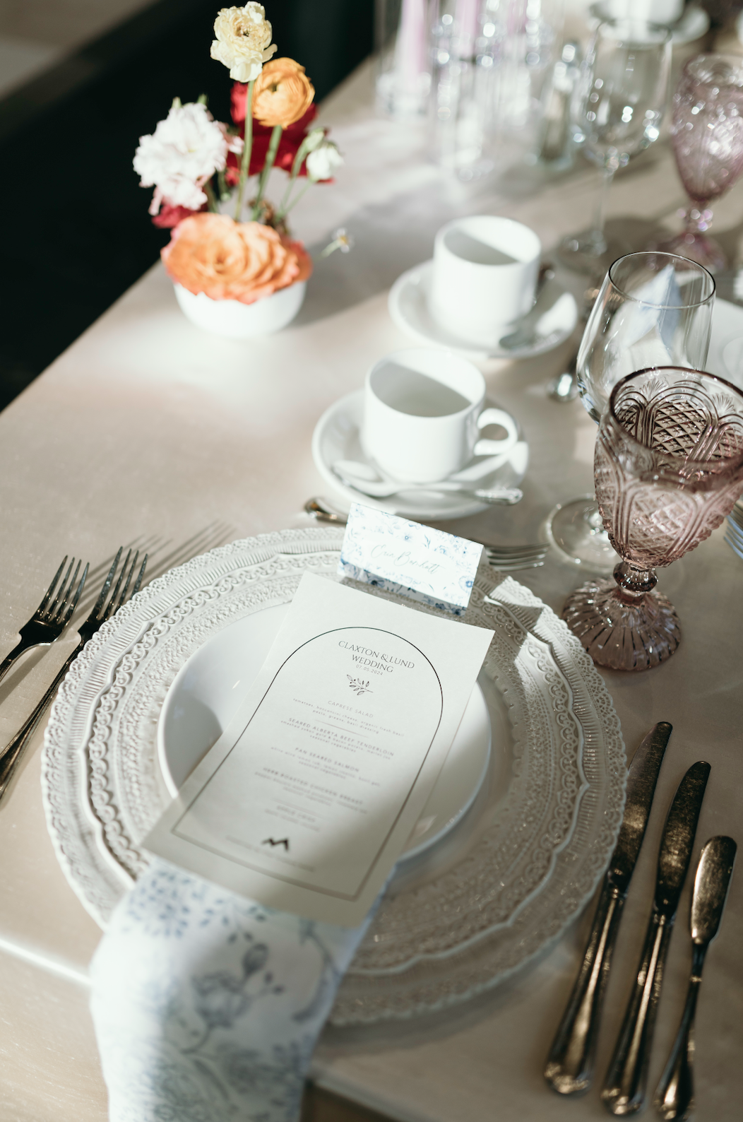 Elegant table setting with lace charger plates, vintage glassware, and bright floral centerpiece at a vibrant The Malcolm Hotel wedding rocky mountain bride reception.