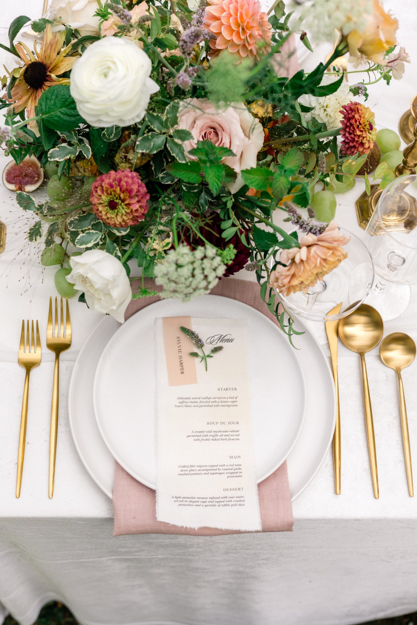 Elegant wedding table setup with gold flatware, blush linen napkins, and lush floral centerpiece during a Waterton Lakes National Park styled shoot.