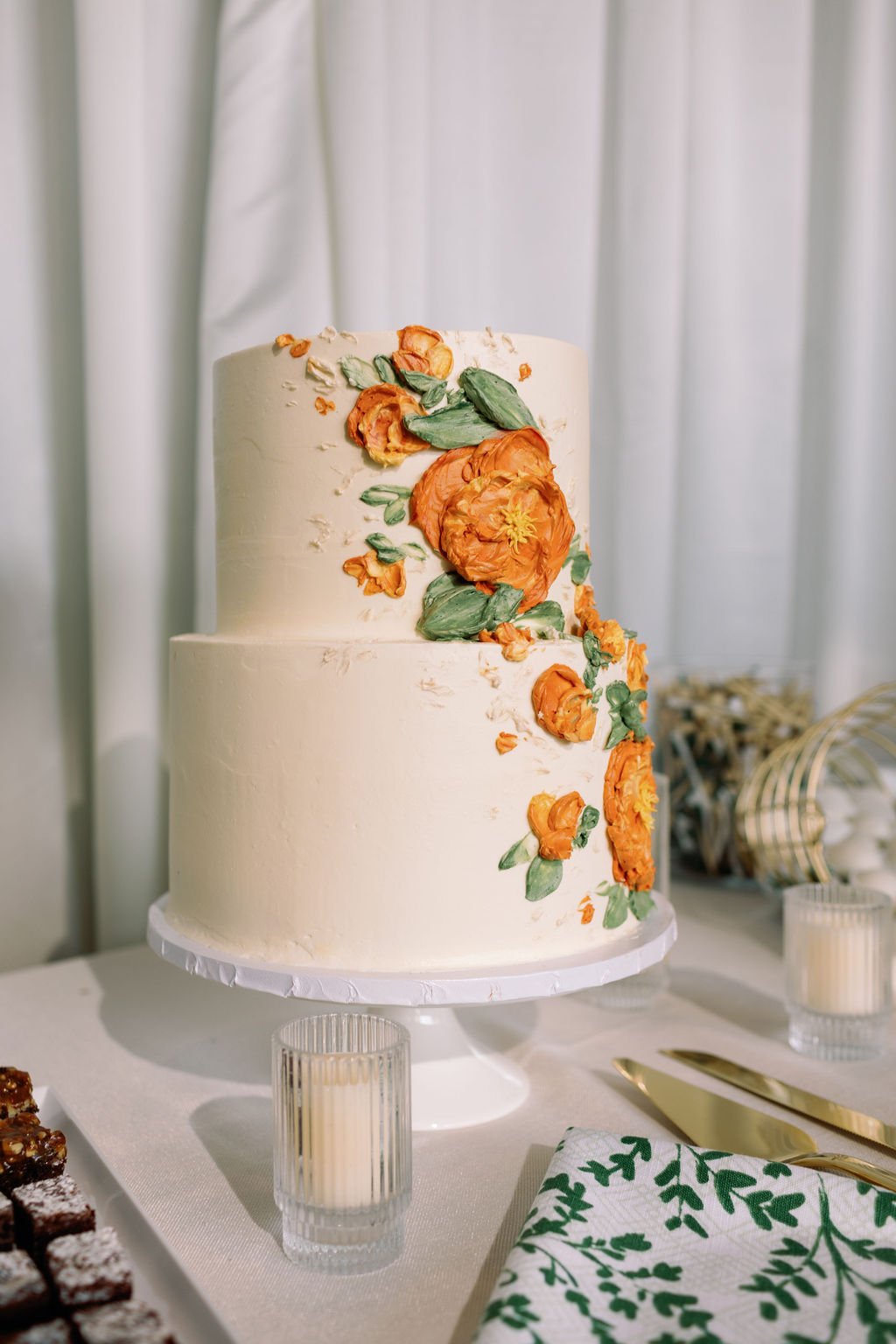 Elegant two-tier wedding cake with hand-piped orange flowers on display at a Zephyr Lodge at Northstar California Resort wedding rocky mountain bride reception.