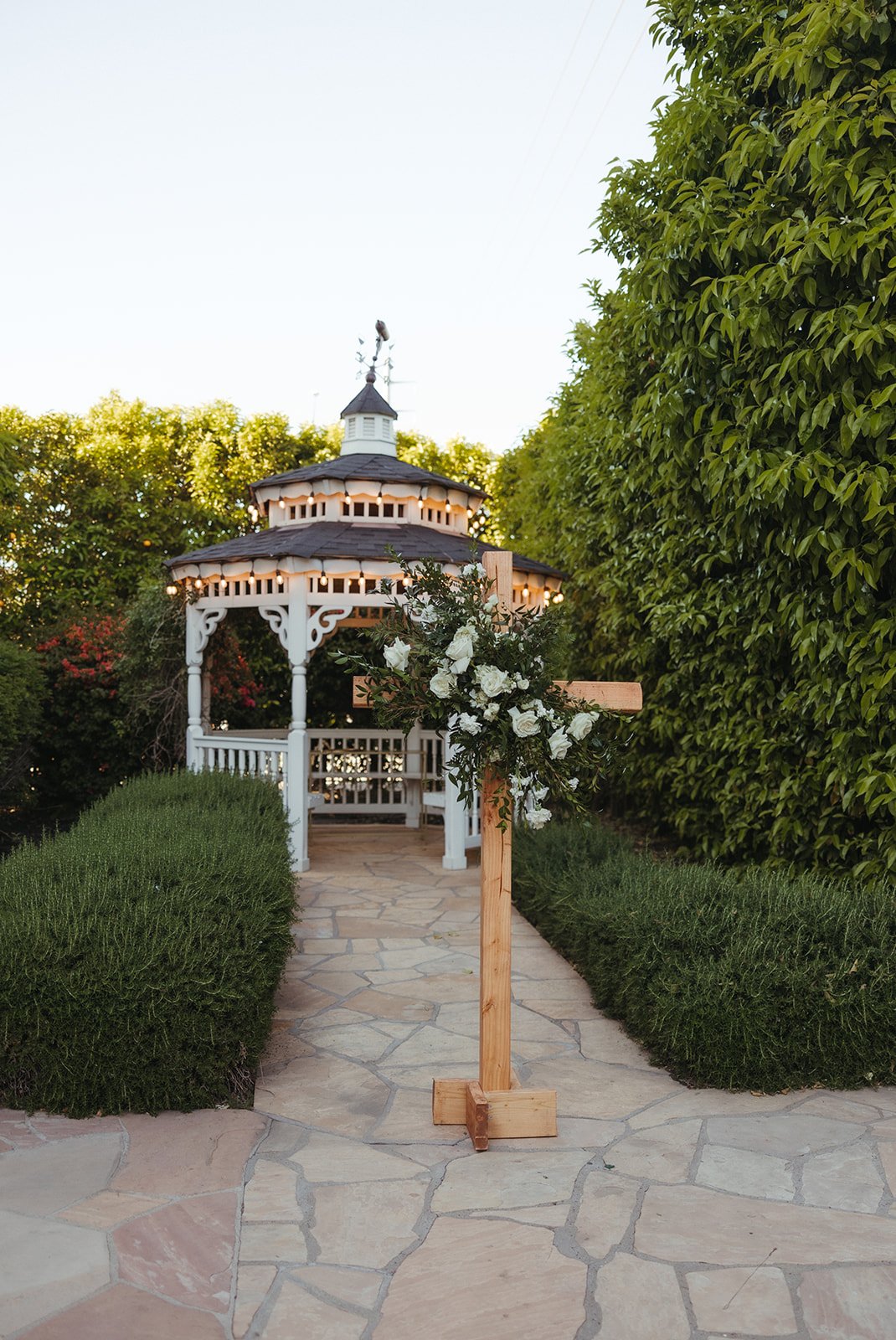 Charming outdoor ceremony setup featuring a white gazebo and floral cross at a mesa arizona wedding rocky mountain bride event.