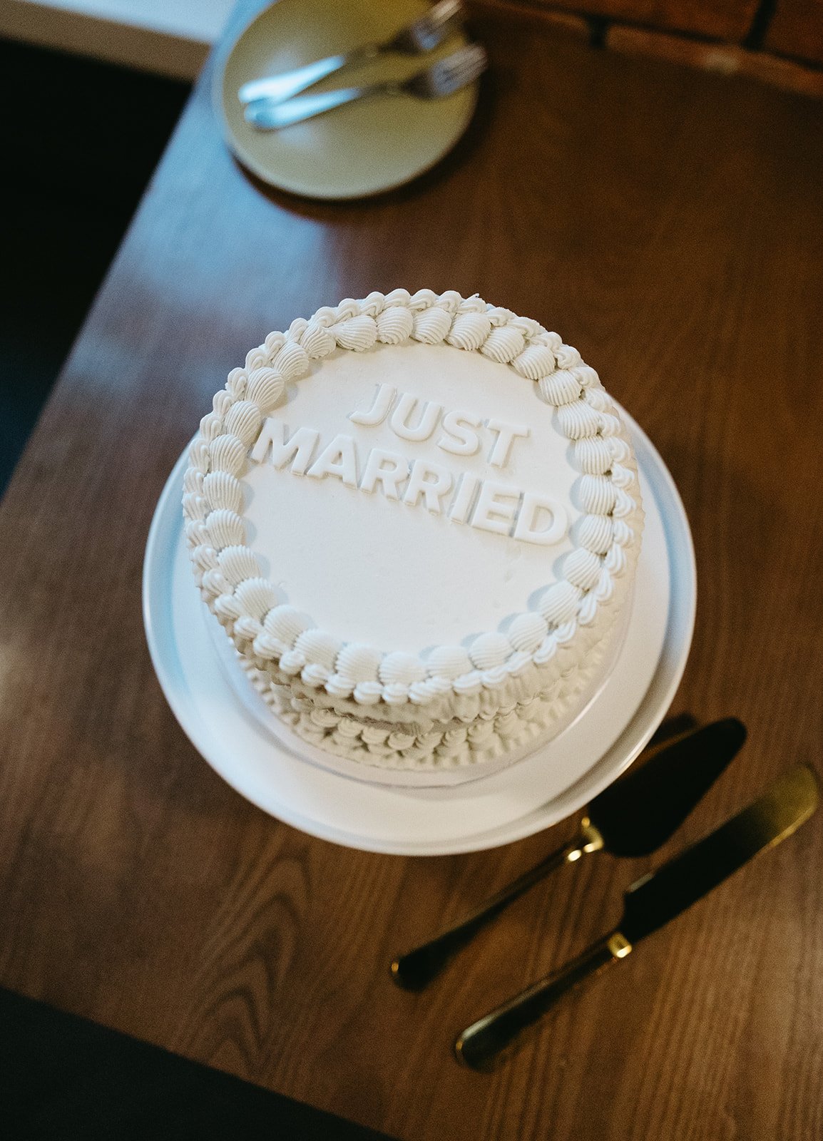 A classic white buttercream cake with “Just Married” lettering, styled simply for a Brazen alberta wedding rocky mountain bride reception.