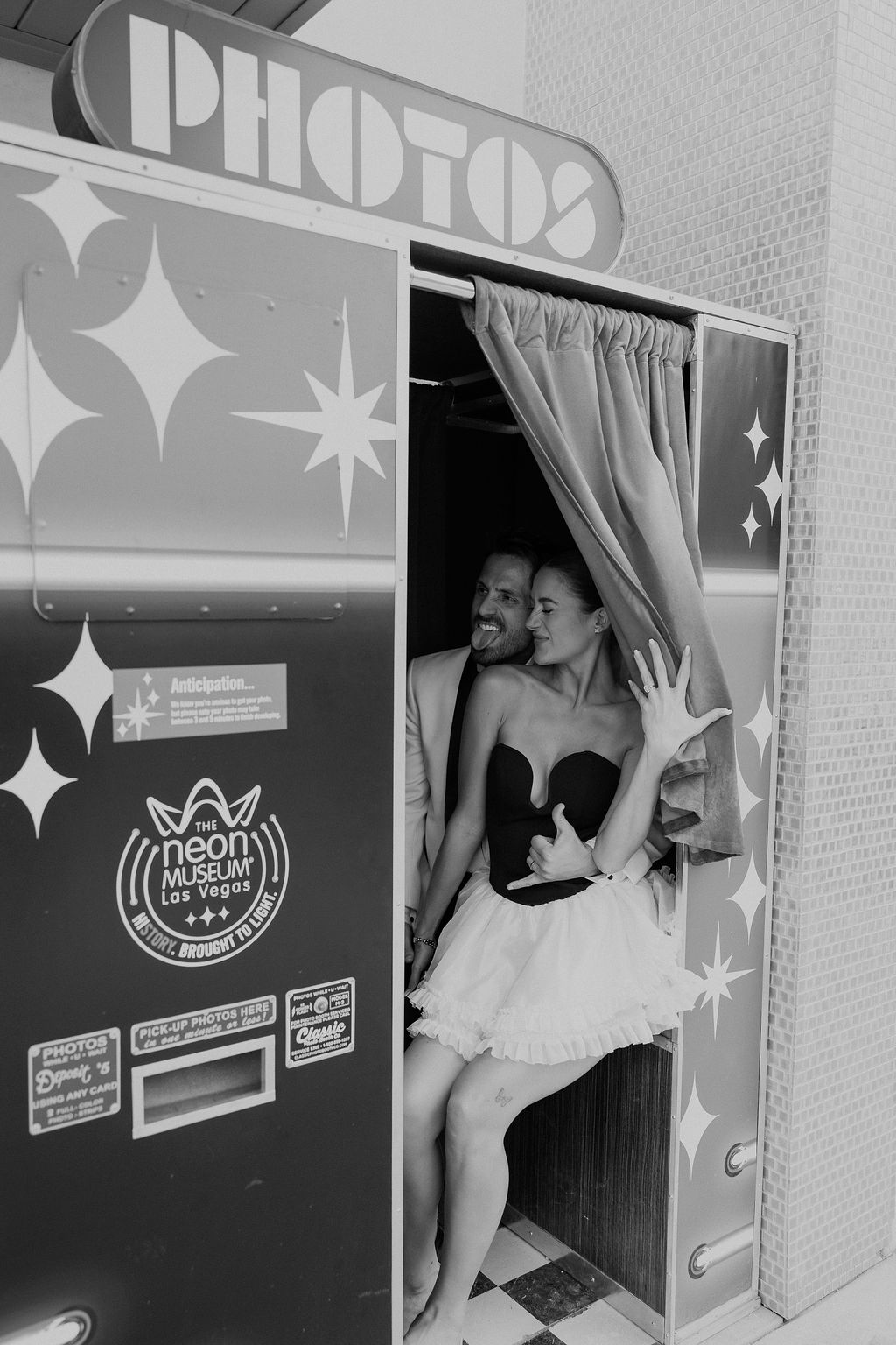 Bride and groom posing inside a retro photo booth at the Neon Museum for their Downtown Las Vegas engagement rocky mountain bride photos.