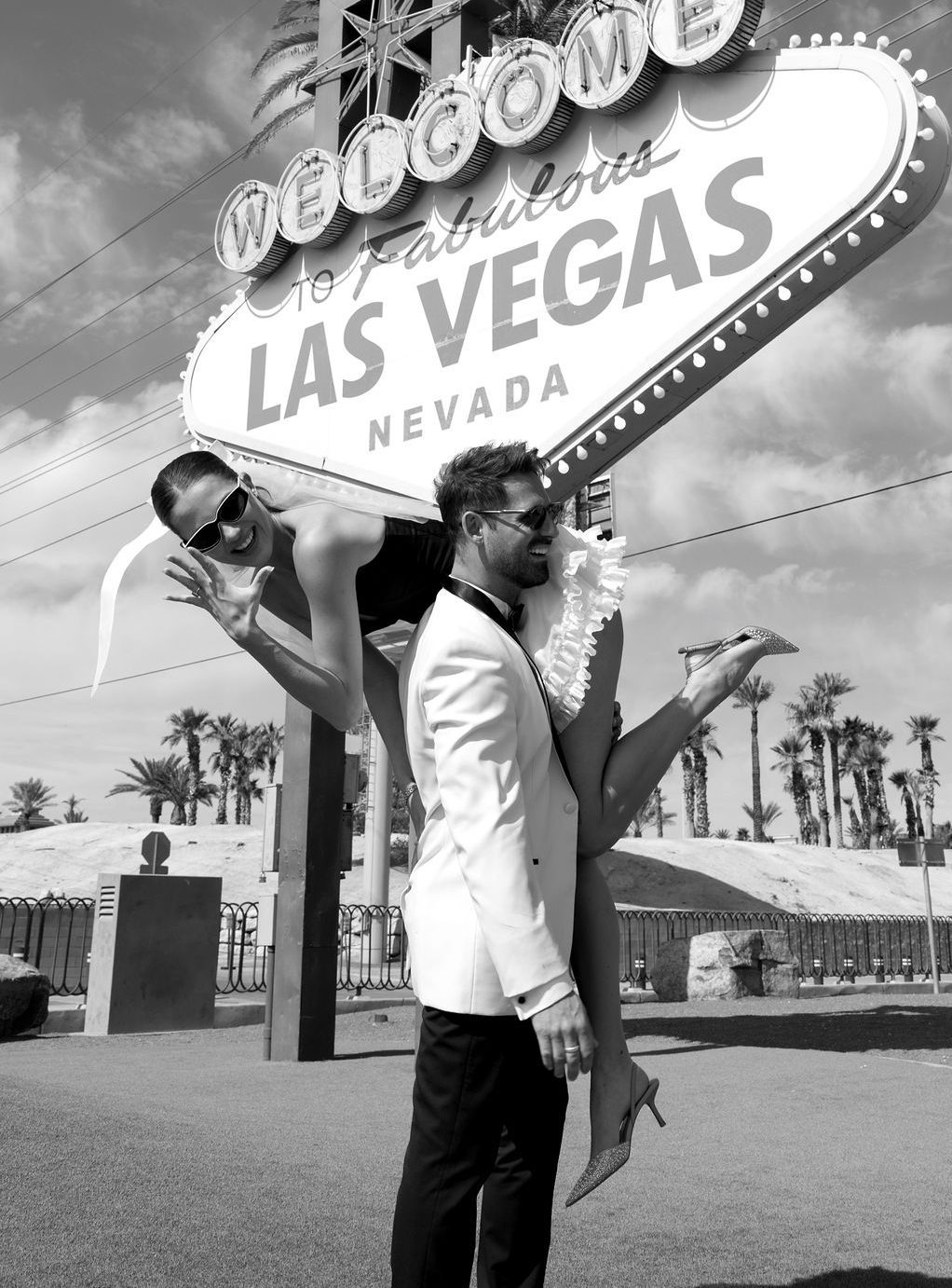Black and white photo of bride on groom’s shoulders in front of the Las Vegas sign during their Downtown Last Vegas engagement rocky mountain bride session.