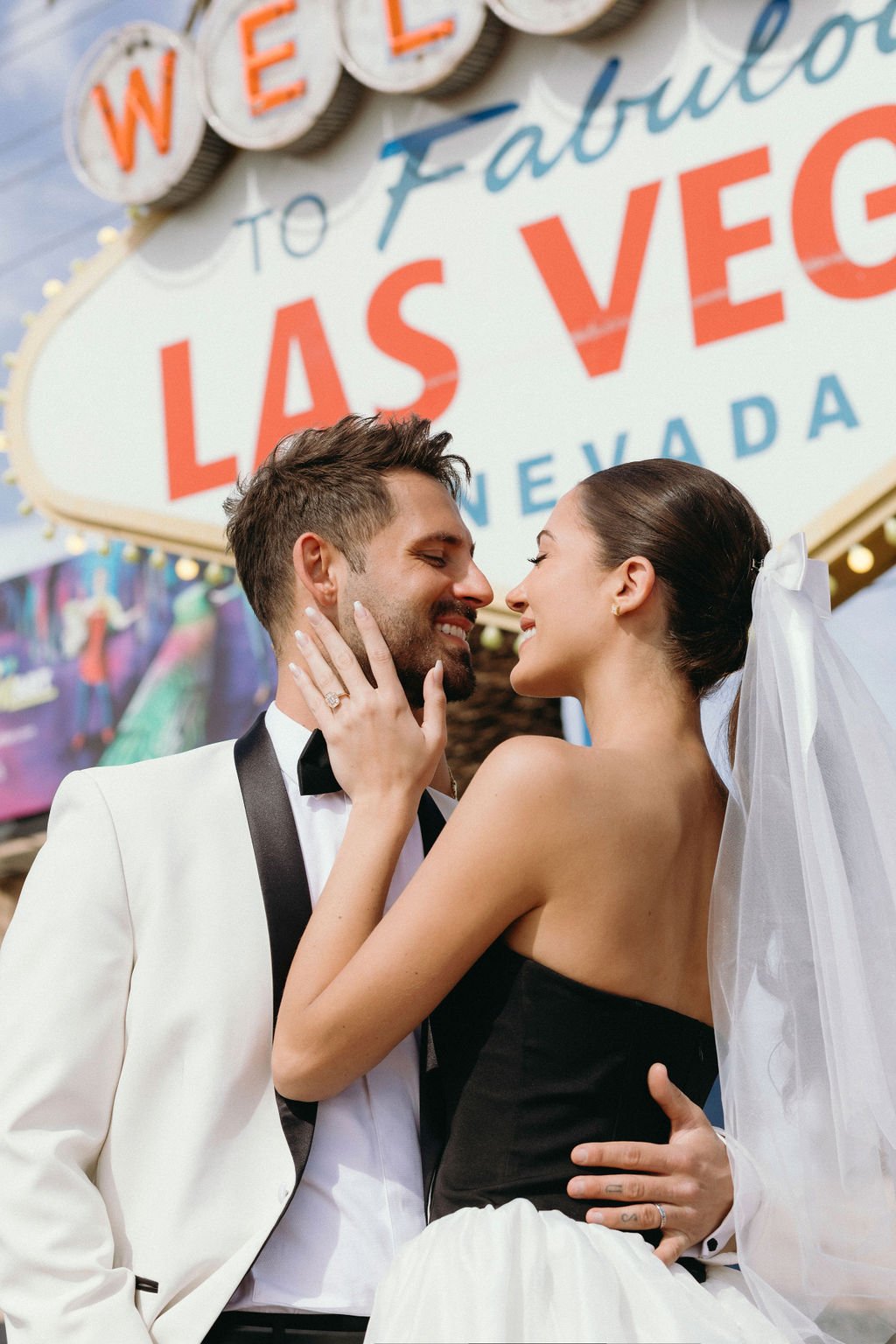 Couple embracing in front of the Welcome to Las Vegas sign during their Downtown Las Vegas engagement rocky mountain bride photo session.