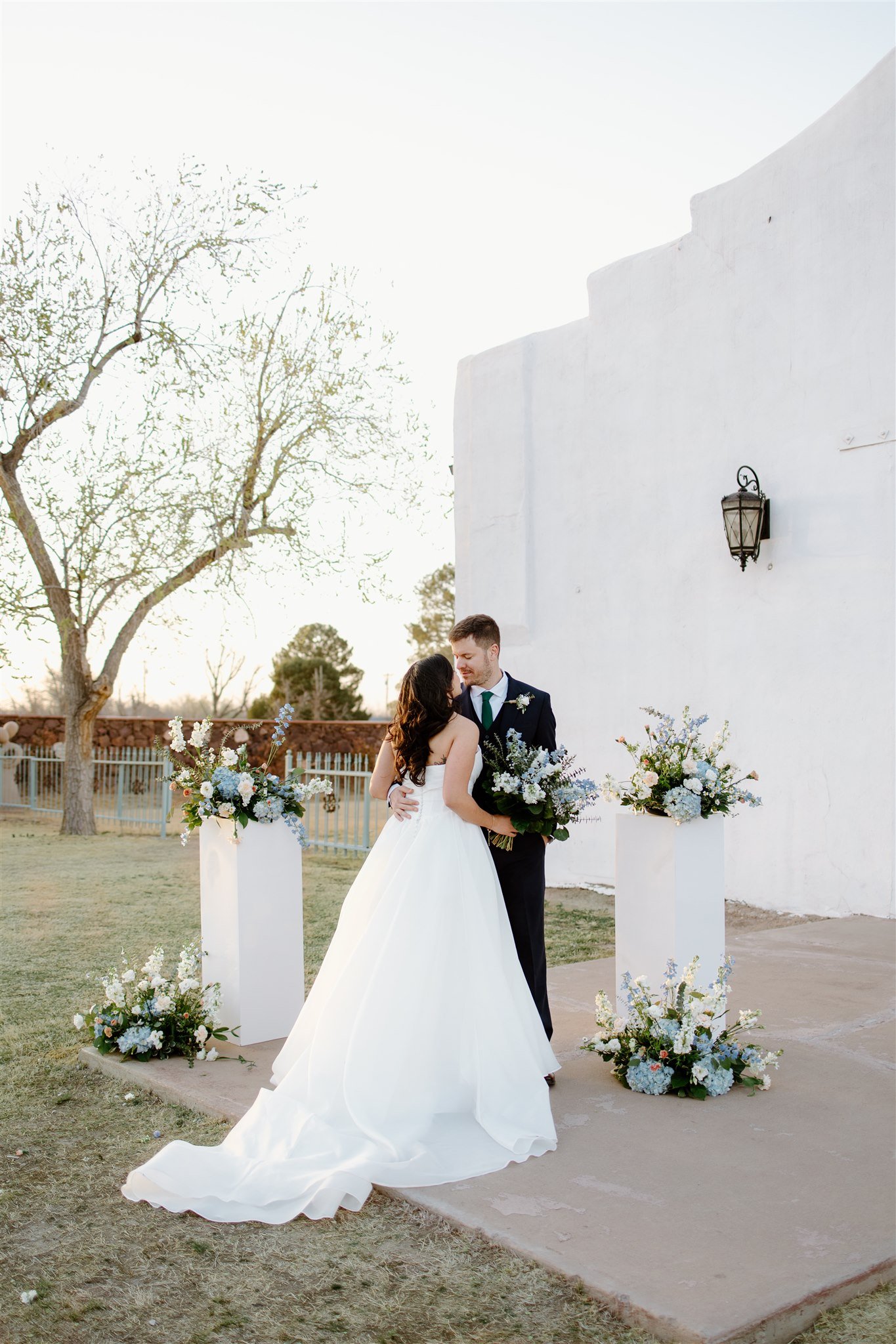 Bride and groom sharing a quiet moment beside floral columns at a Los Portales New Mexico spring wedding rocky mountain bride.