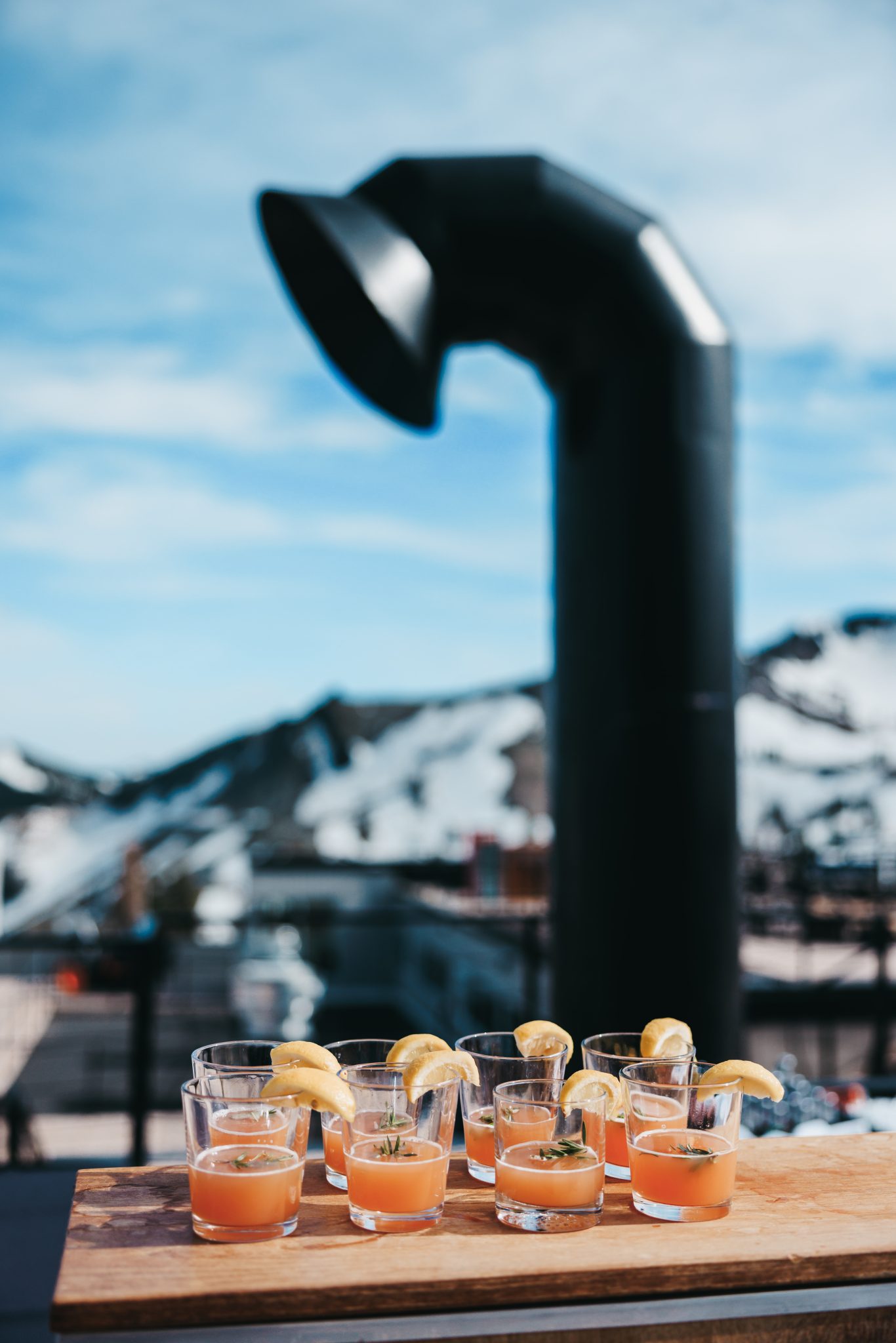 Signature grapefruit cocktails with lemon garnishes displayed outdoors with snowy mountain views during a Palisades Tahoe spring wedding rocky mountain bride.