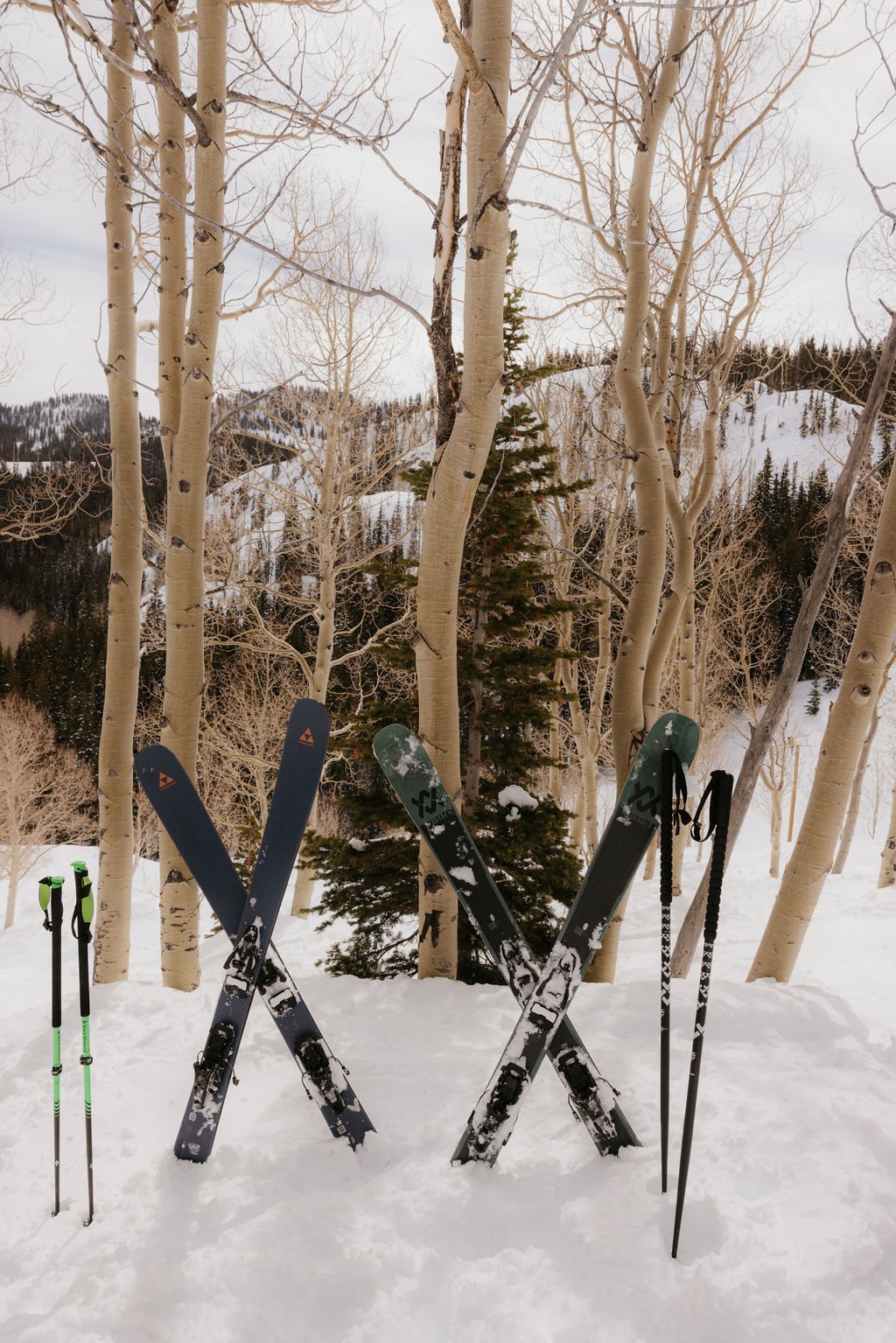 A close-up of crossed skis and poles in fresh snow surrounded by aspen trees, captured during a Spring Brighton Resort elopement.