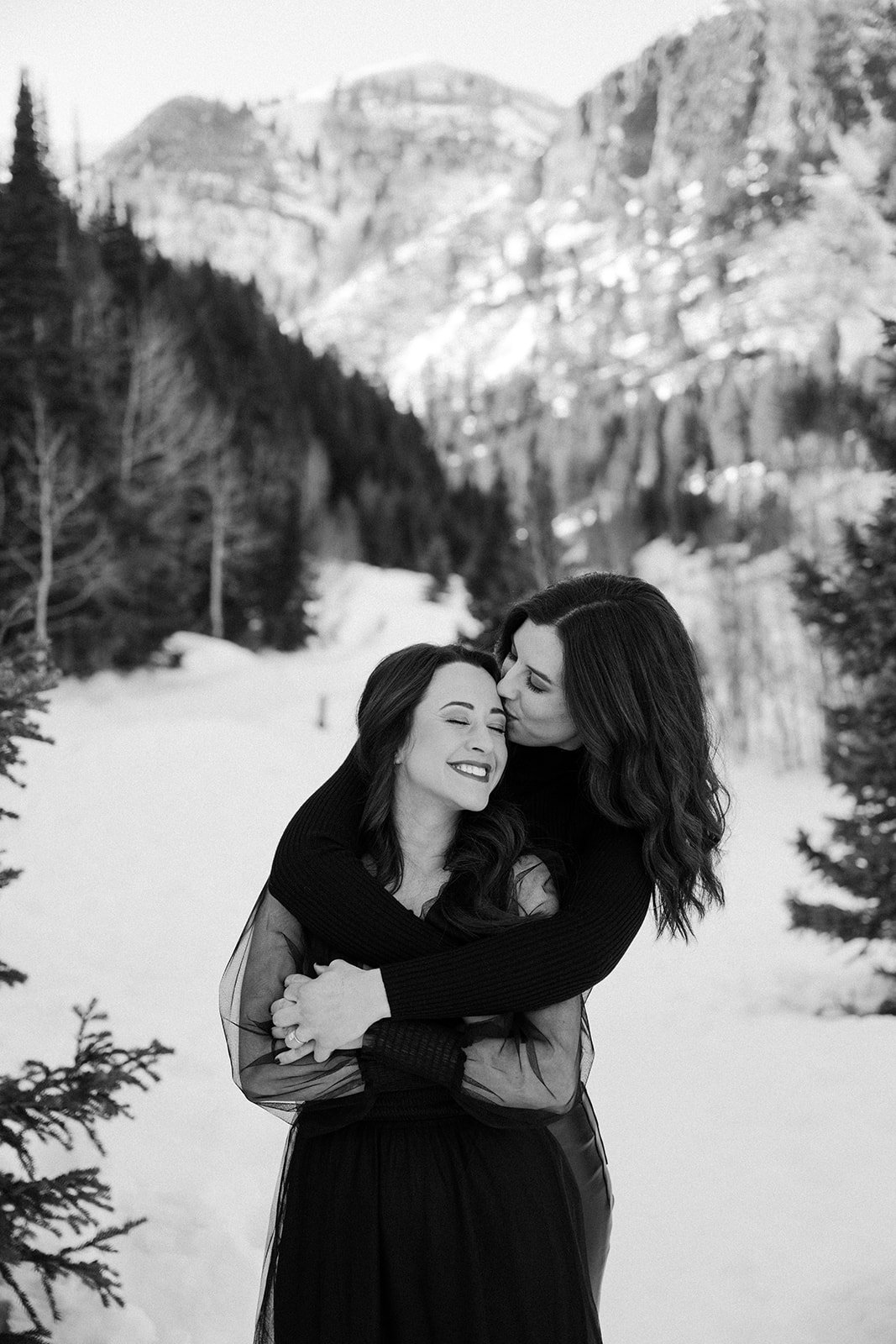 A couple embraces in the snowy Utah mountains during their Tales of Sonder Utah engagement session rocky mountain bride.