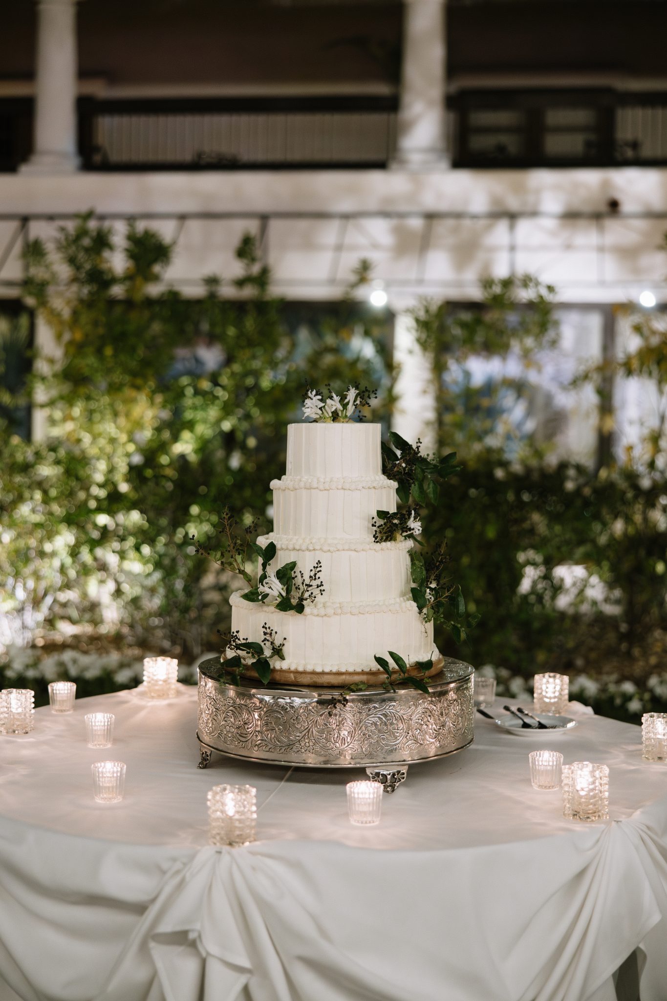 Classic three-tiered white wedding cake with greenery at The Scottsdale Resort & Spa fall wedding rocky mountain bride, surrounded by votive candles.