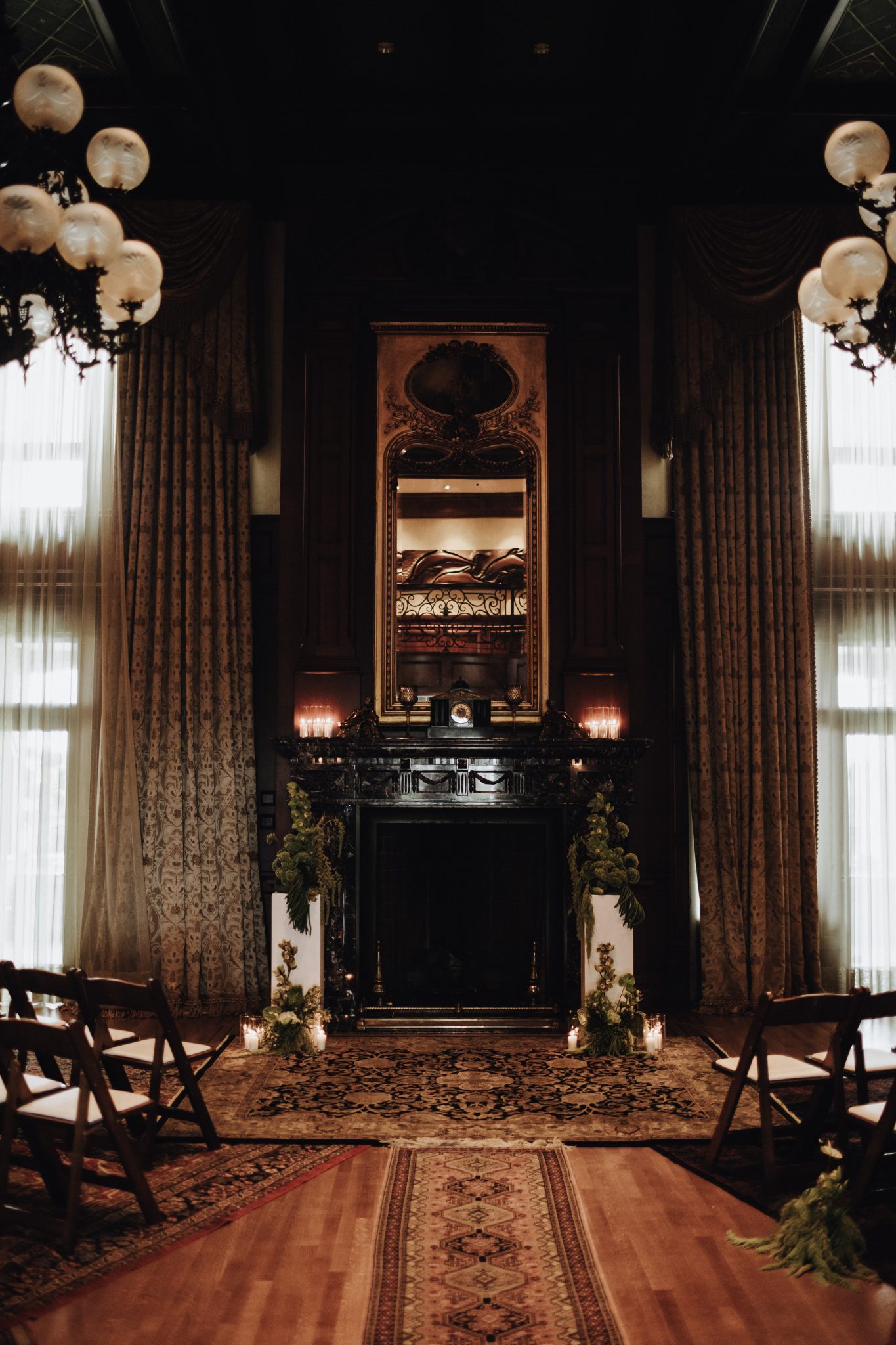 Elegant indoor ceremony setting with vintage chandeliers, a grand fireplace, and classic wooden chairs for a Vancouver wedding private estate rocky mountain bride.