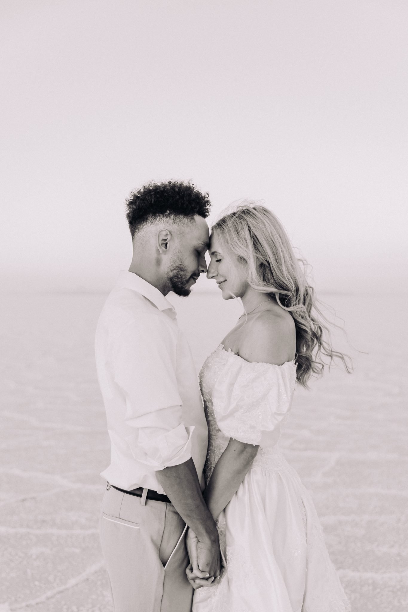 Romantic black and white portrait of couple embracing closely during a Bonneville Salt Flats engagement session Niki Baldwin Photography rocky mountain bride.