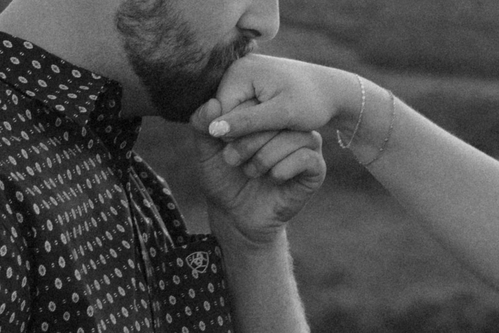 A romantic black-and-white detail shot of a man kissing his fiancée’s hand, taken during the Christensen Edits Photography Utah engagement session rocky mountain bride.