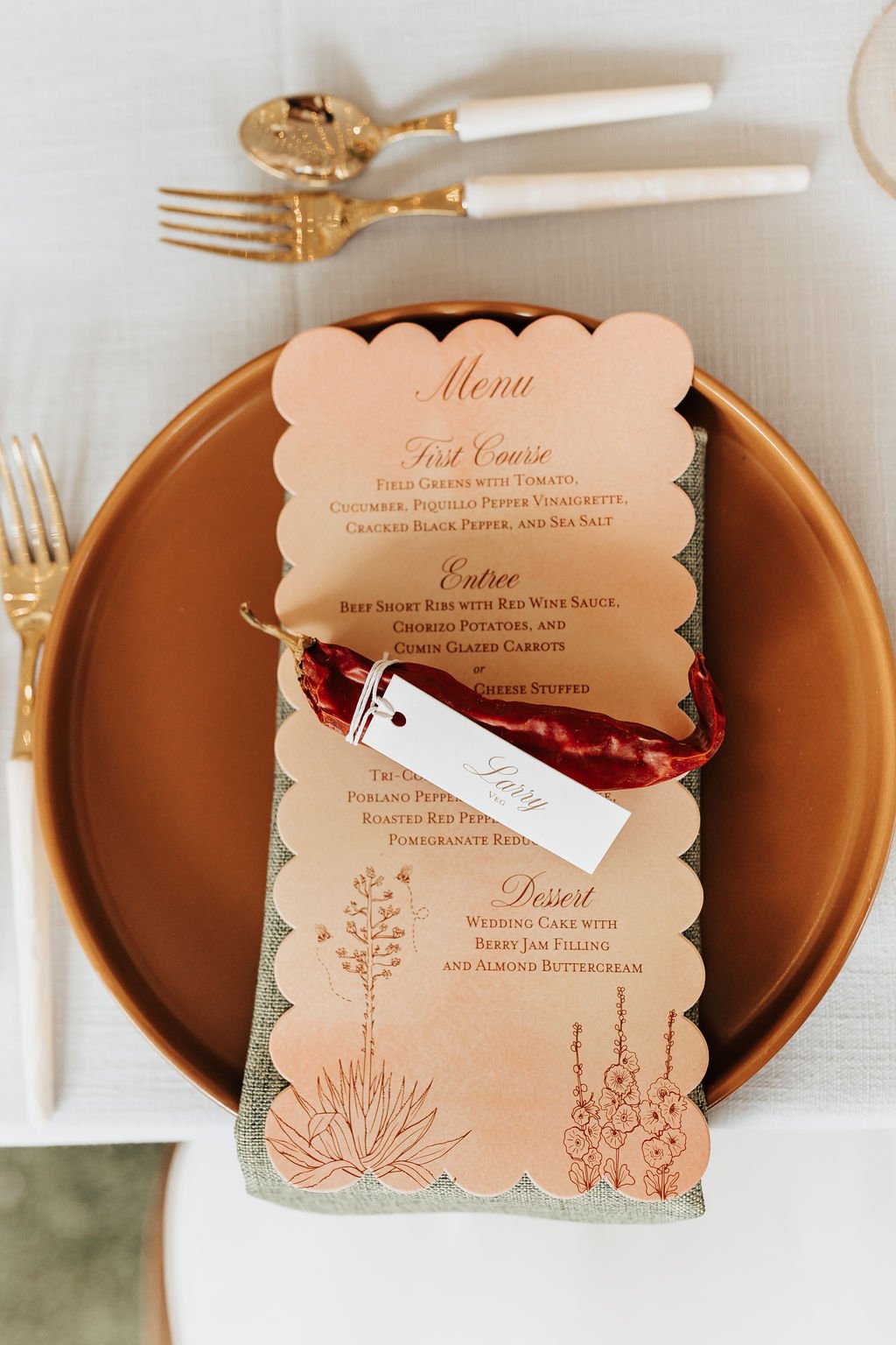 Southwestern-inspired place setting featuring a scalloped-edge menu, gold flatware, and personalized name tag with a chili pepper at a La Posada de Santa Fe wedding rocky mountain bride reception.