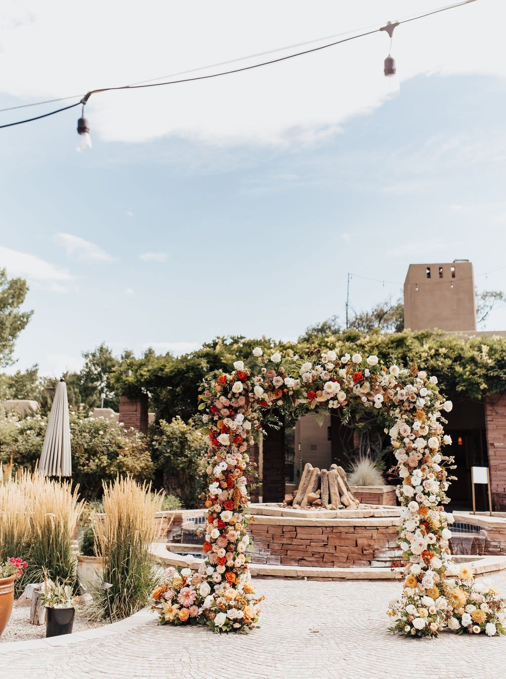 Lush floral ceremony arch with autumn-hued roses and greenery in a courtyard setting at a La Posada de Santa Fe wedding rocky mountain bride ceremony.
