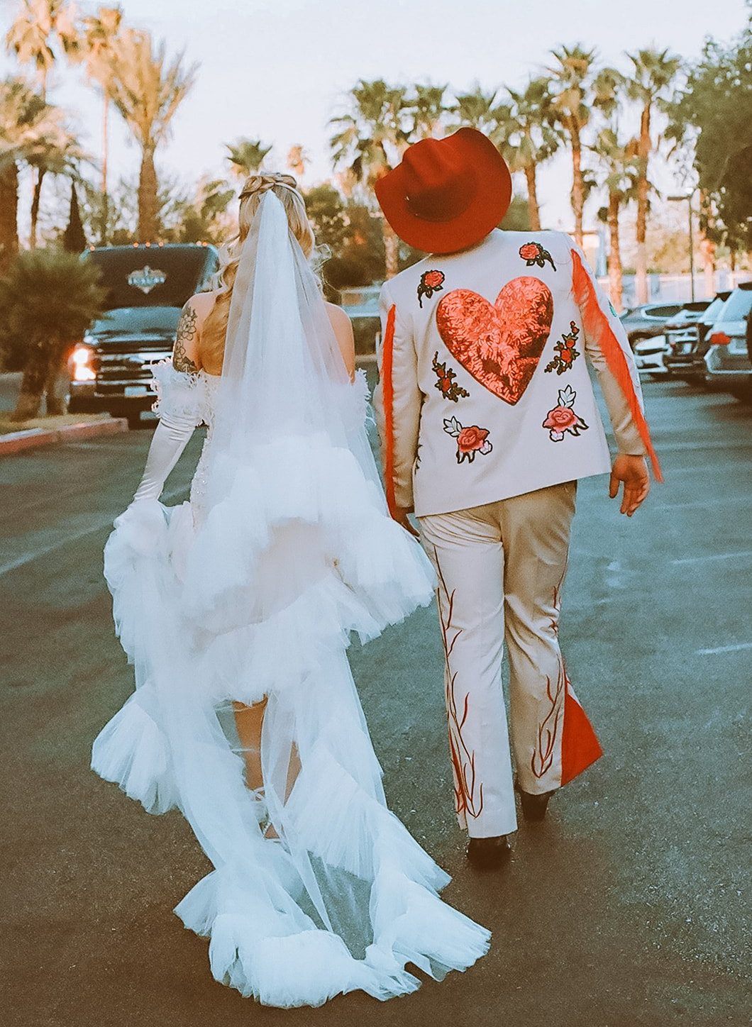 Stylish couple in bold heart-themed wedding attire walking outside after their Little White Wedding Chapel summer elopement rocky mountain bride ceremony.