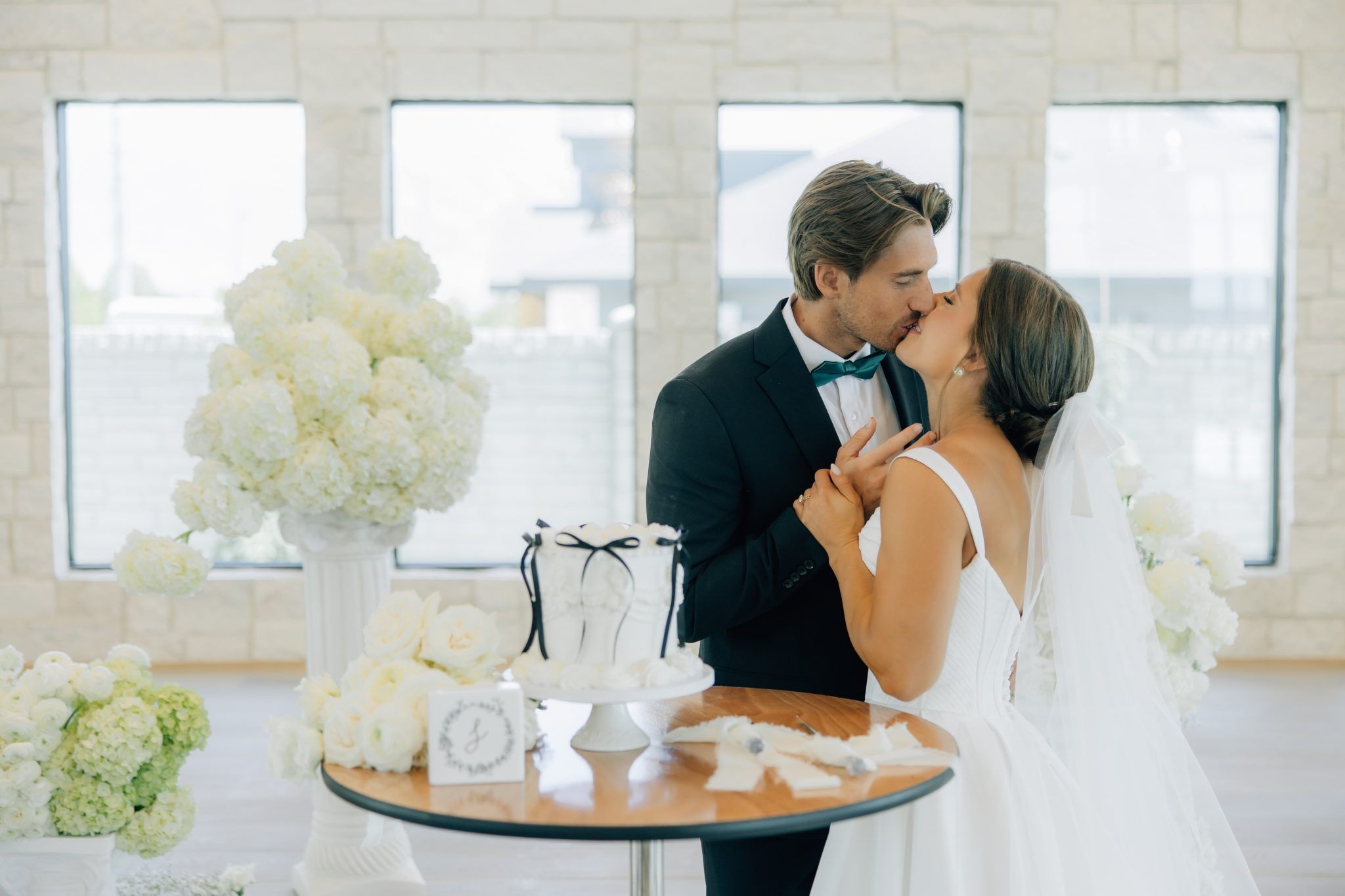 bride and groom kissing next to their cake