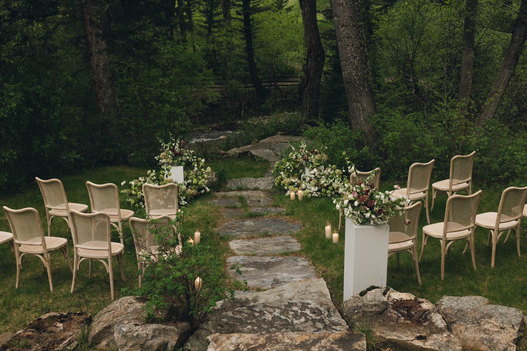 Intimate ceremony space with natural wood chairs, candlelight, and floral pillars along a stone path at a Sanctuary at Crow Hollow Ranch wedding inspiration rocky mountain bride location.