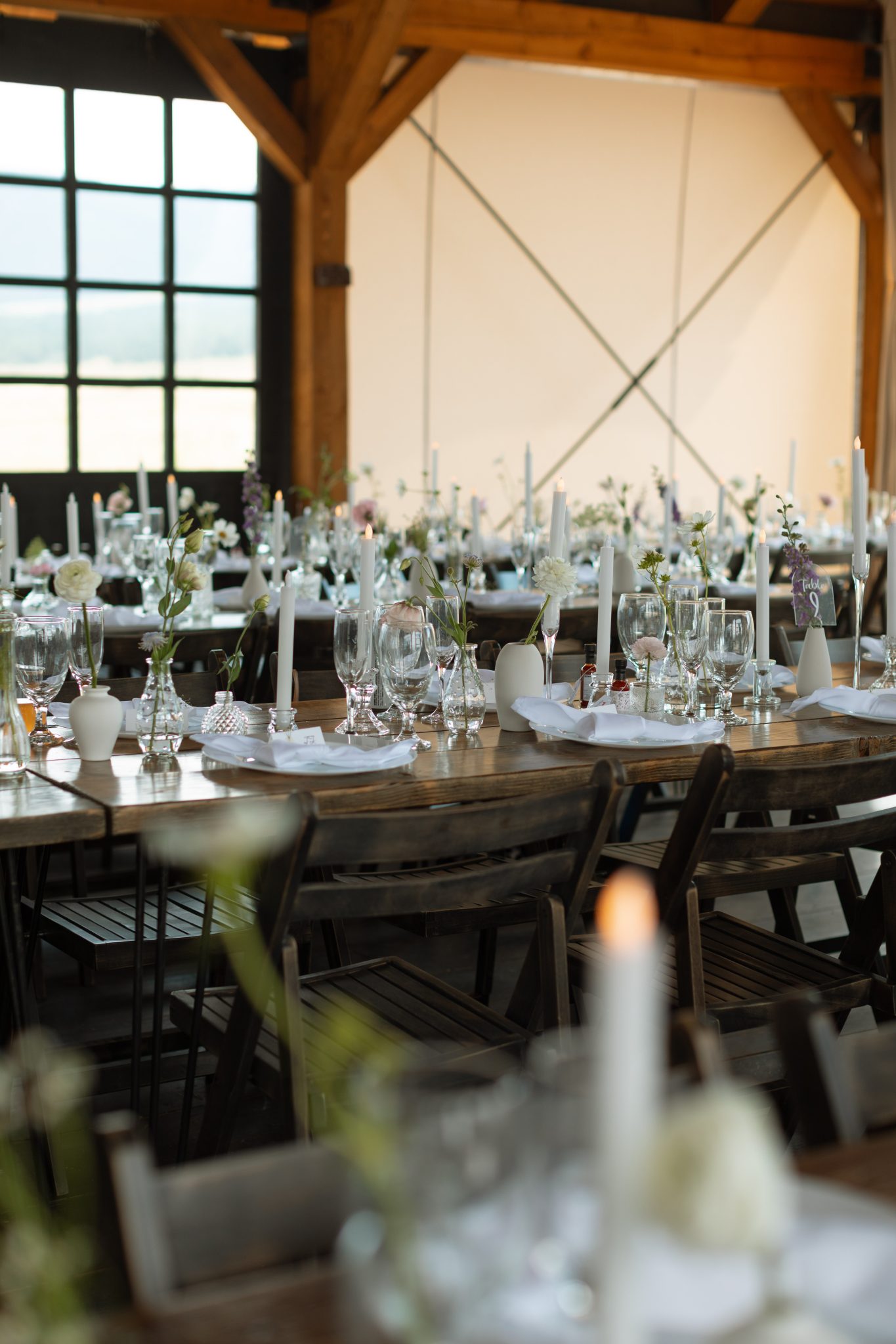 Romantic reception tables with minimalist floral centerpieces and taper candles at a Three Peaks Ranch wedding with Sophie Catherine Photo rocky mountain bride.