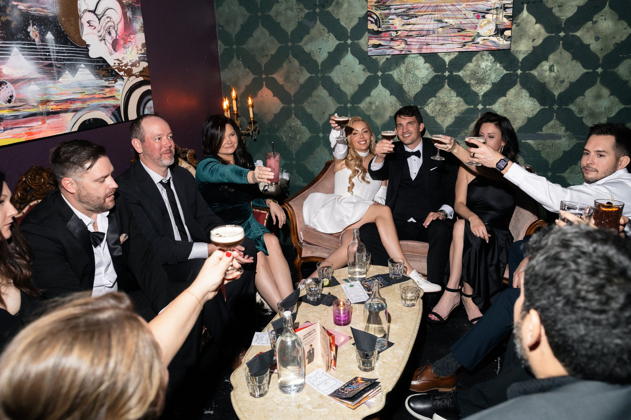 The wedding party raising glasses for a celebratory toast in a cozy lounge, enjoying the night of the las vegas winter elopement rocky mountain bride.
