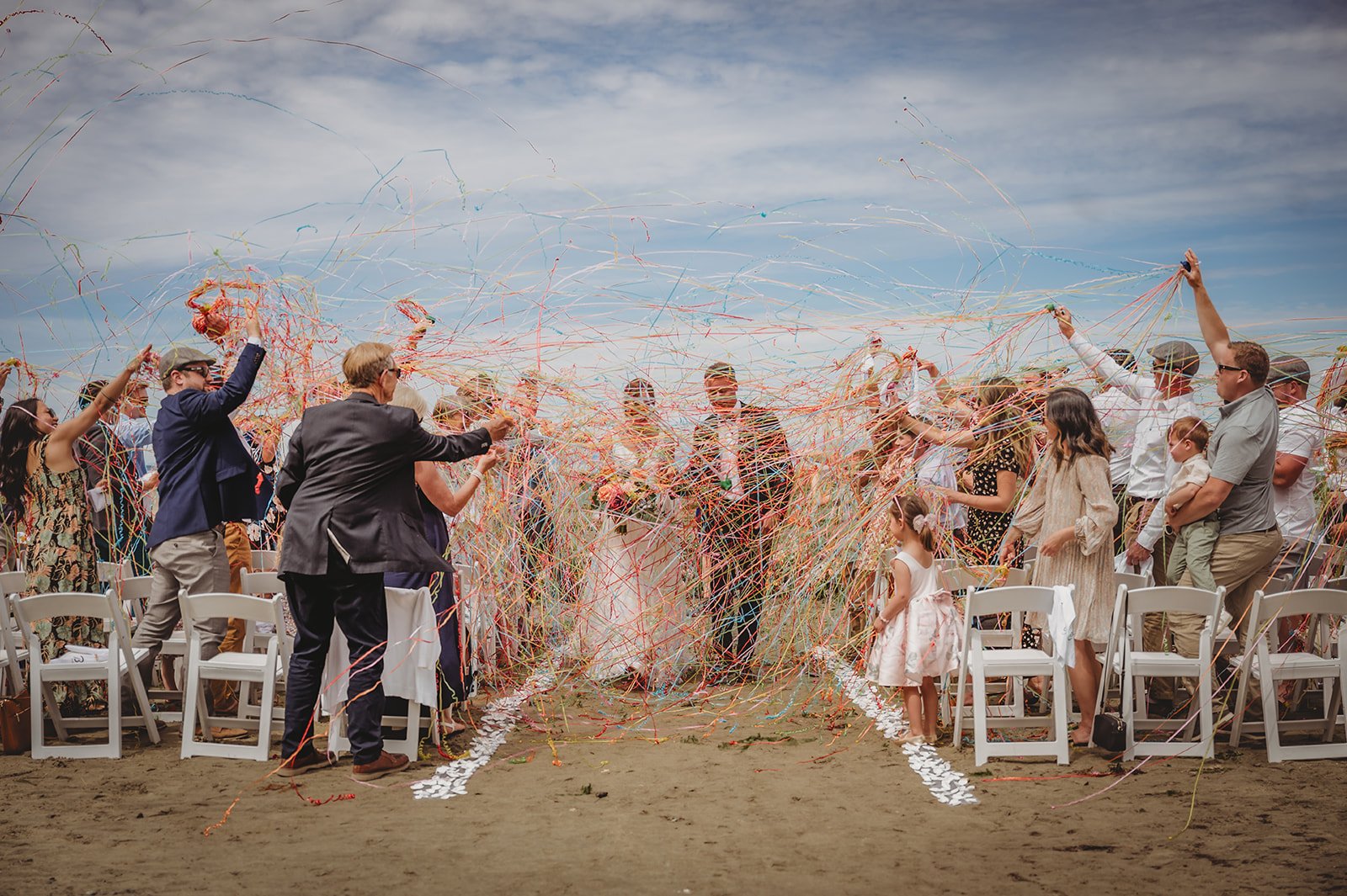 Guests celebrate with colorful streamers as the couple walks down the aisle at a private estate wedding in British Columbia Rocky Mountain Bride.