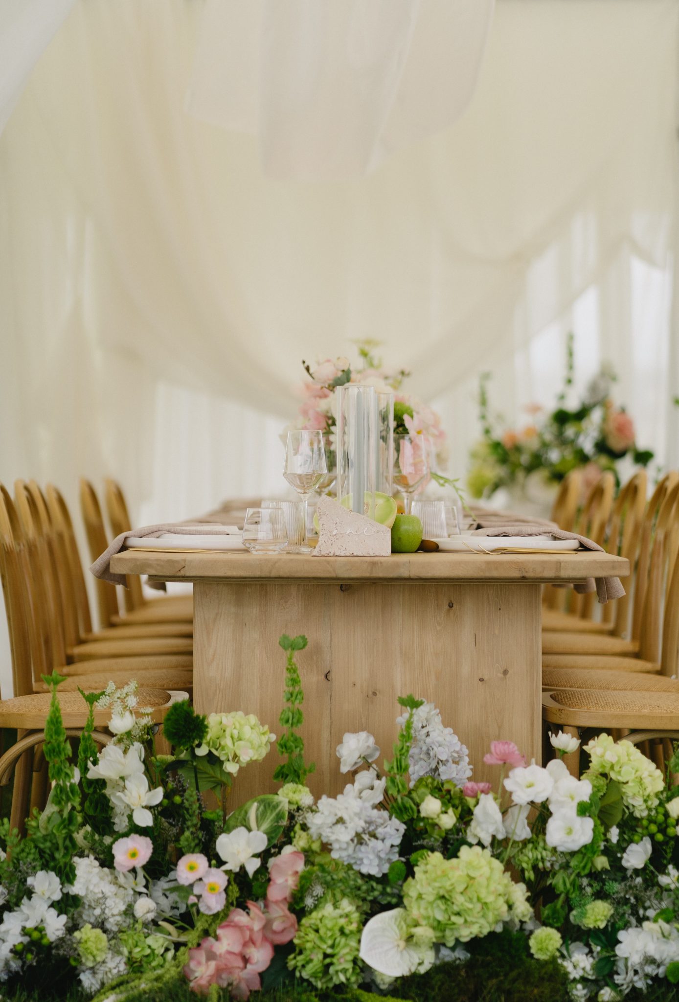 Long wooden reception table with neutral linens and lush floral arrangements in white, pink, and green — Aurora Valley Farm wedding inspiration british columbia rocky mountain bride