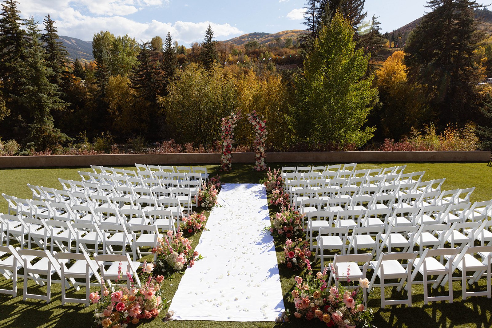White chairs and floral arrangements along an aisle at a Bailey Richy Events & Design colorado wedding at The Westin Riverfront Resort & Spa rocky mountain bride.
