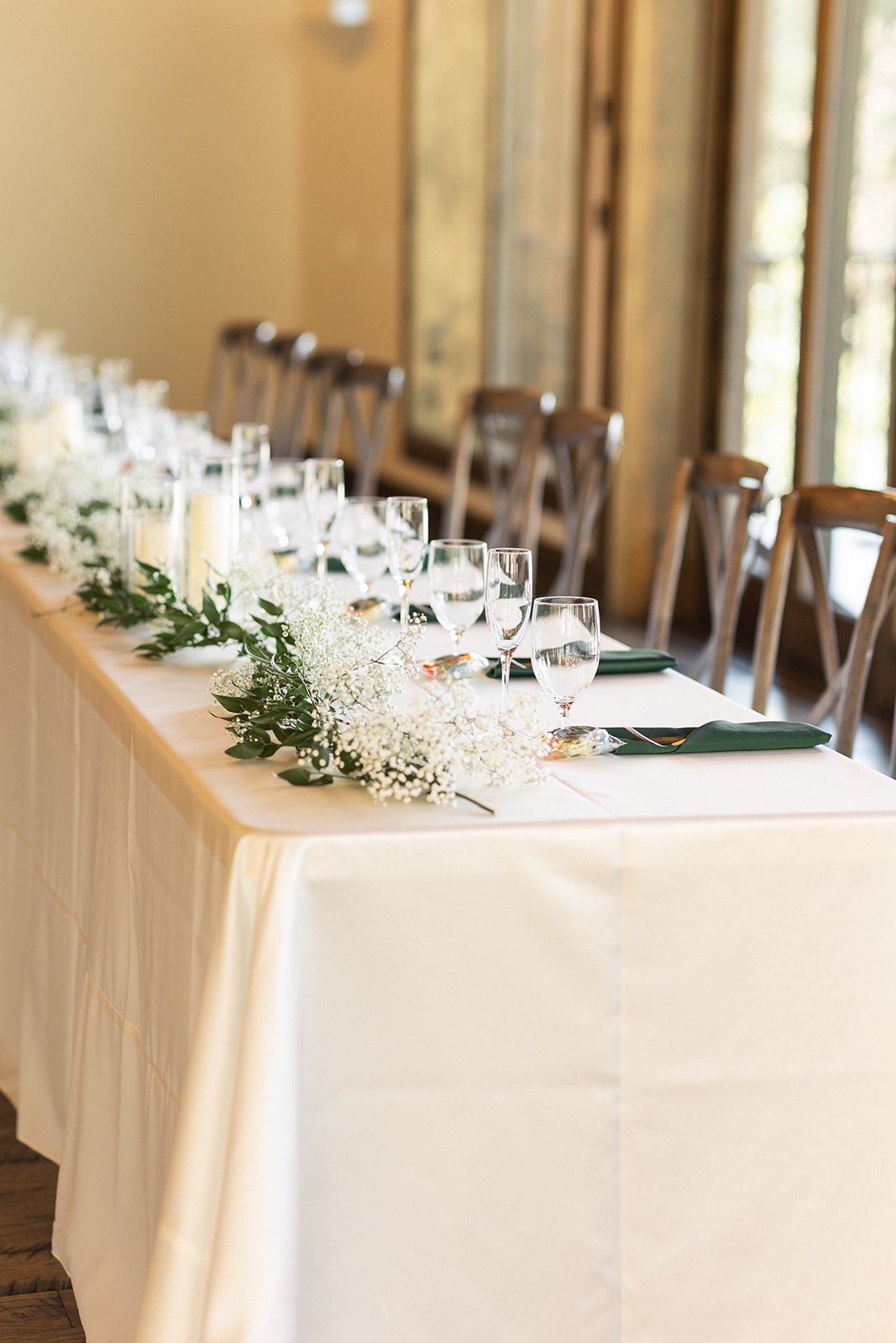 Long reception table with greenery, candles, and white linens styled for a Black Canyon Inn summer wedding rocky mountain bride.