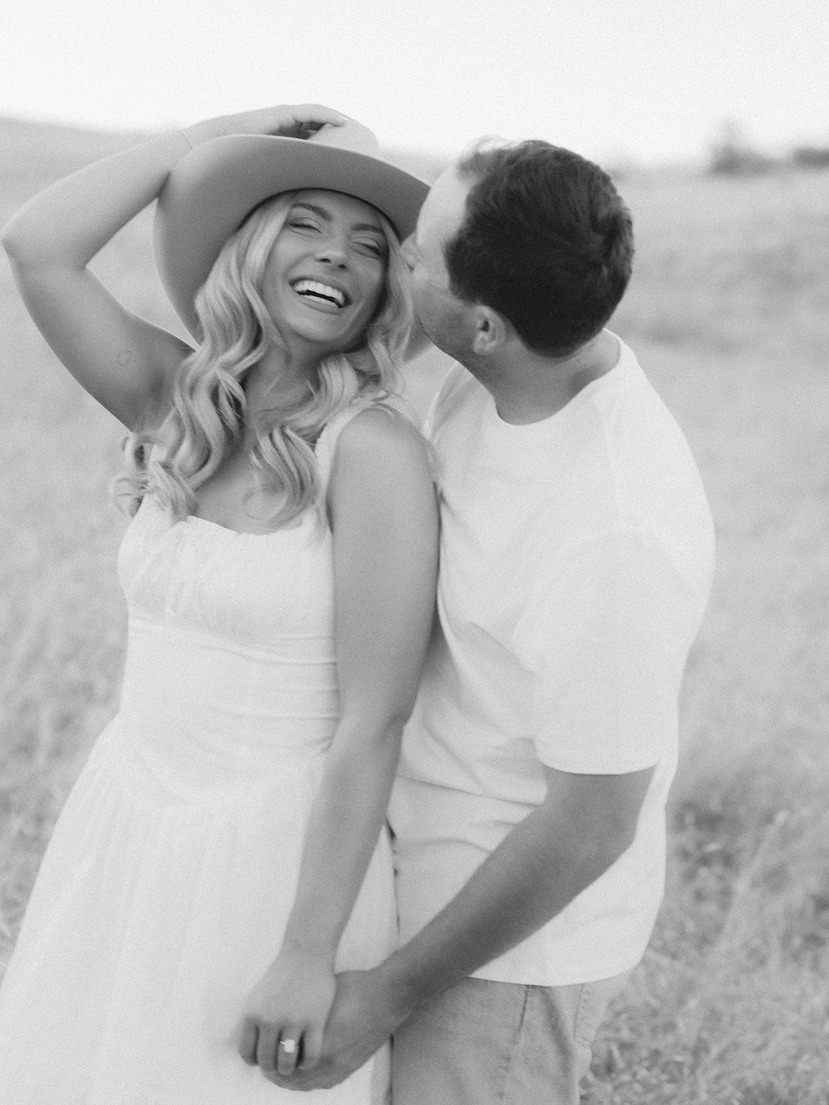 Black and white photo of the couple in Idaho's fields while enjoying the moment with laughter for a Boise Idaho engagement session with Kayla Lucio Photo rocky mountain bride