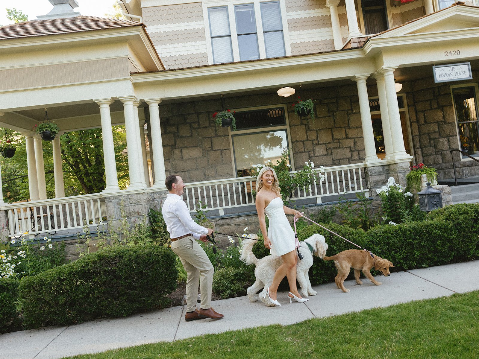 Walking through the neighborhood with their dogs as she was a cute white dress for a Boise Idaho engagement session with Kayla Lucio Photo rocky mountain bride