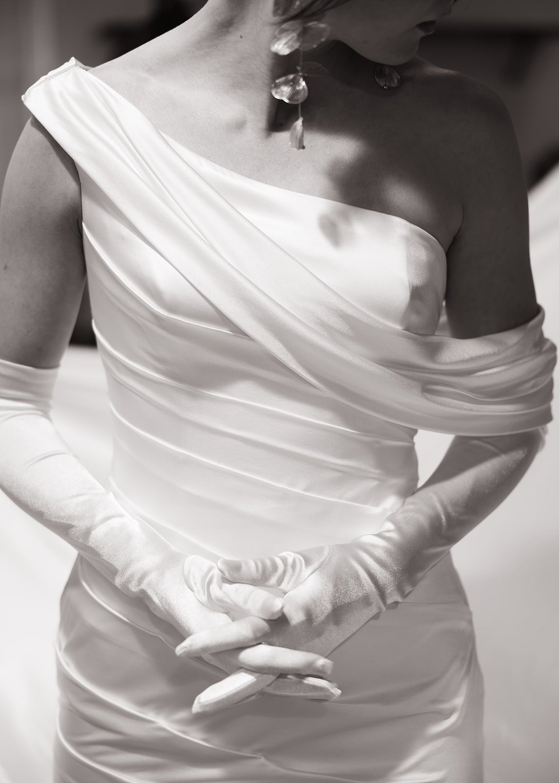 Close-up of an elegant off-the-shoulder satin wedding gown with ruched detailing and gloves at a Desert Botanical Garden spring wedding rocky mountain bride.