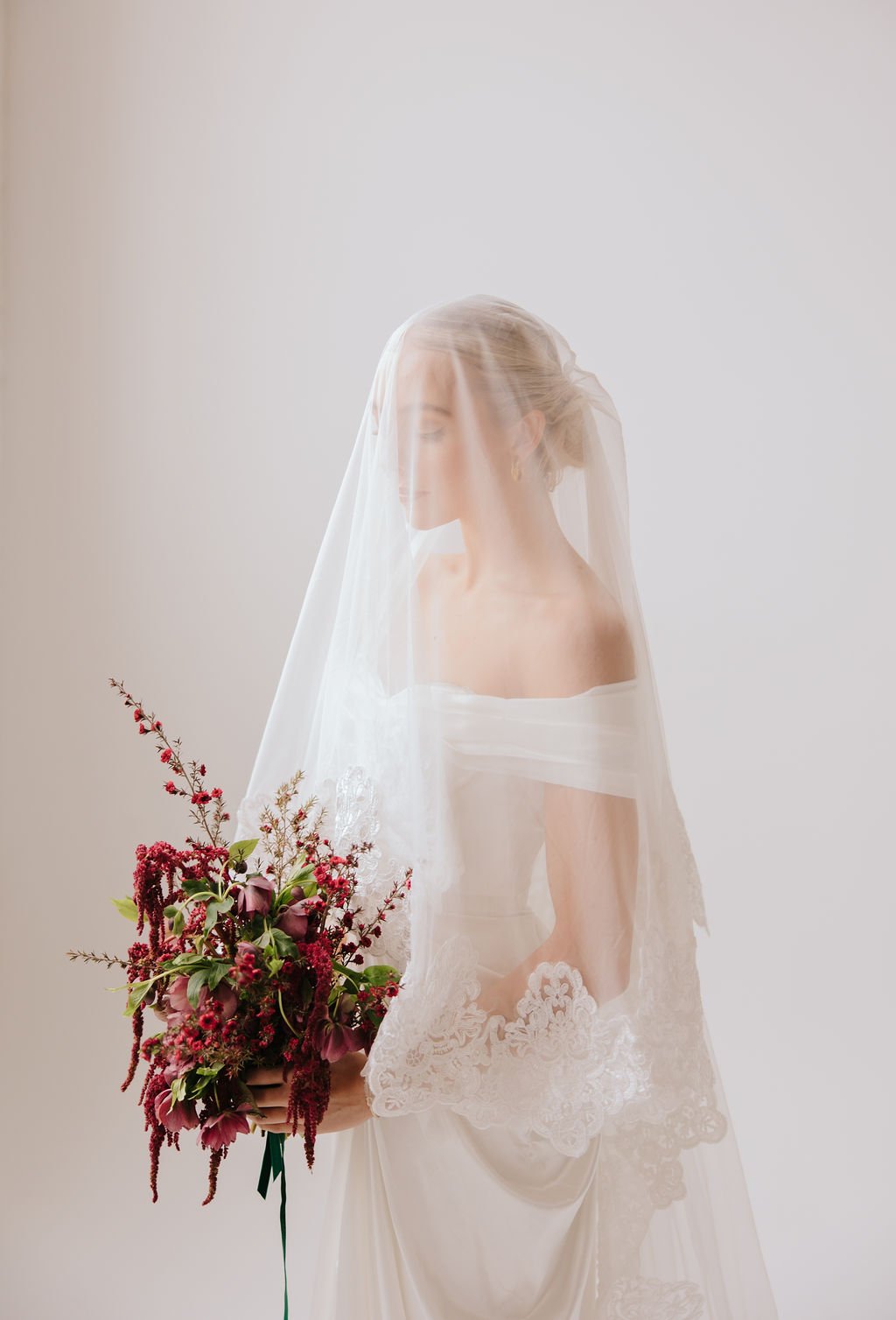 Bride holding cascading floral bouquet during Emileigh Hoisington styled shoot salt lake city utah rocky mountain bride, featuring romantic lace-trimmed veil.