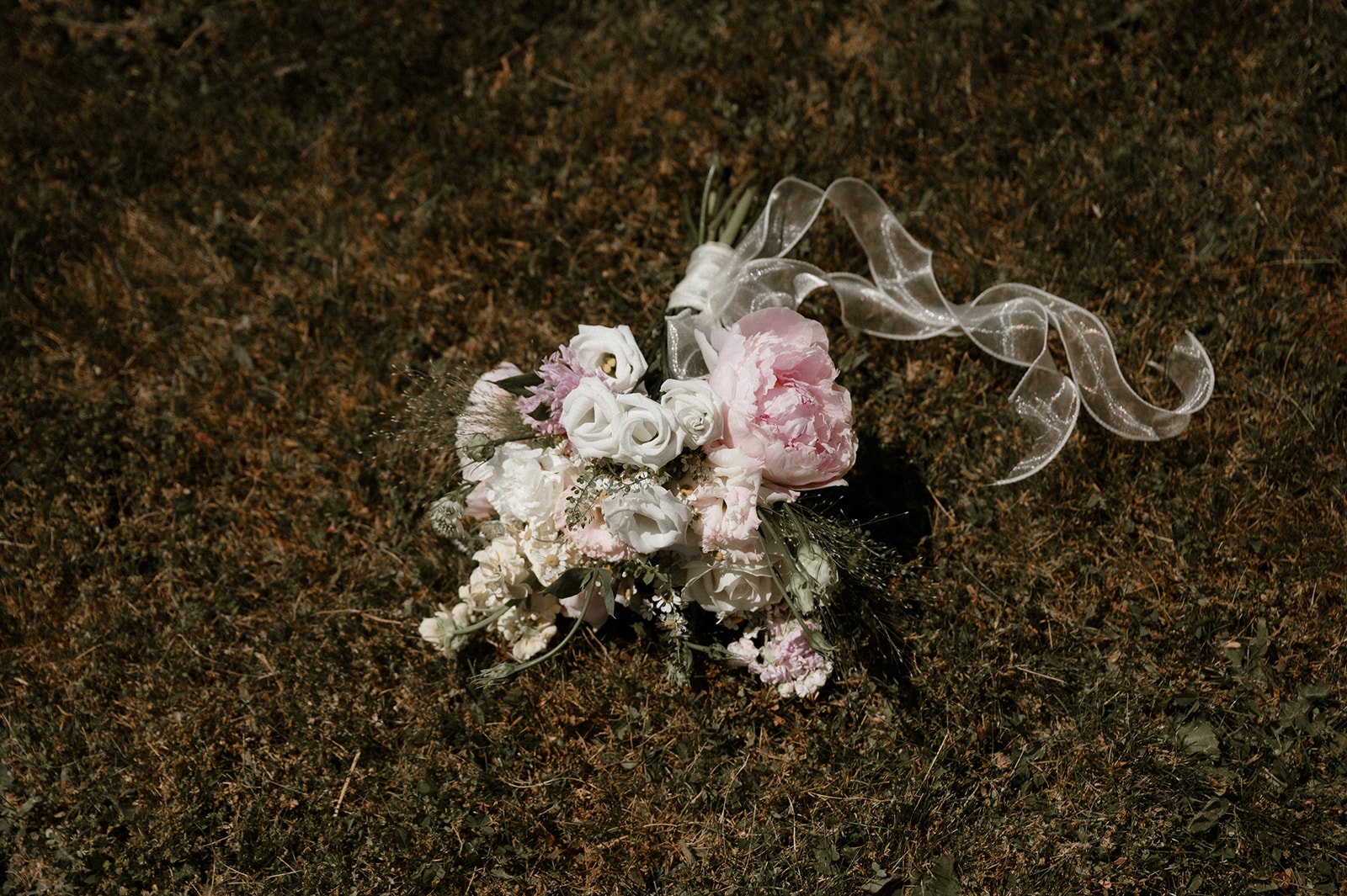 Romantic pastel bridal bouquet with roses and peonies resting on the ground at a Homestead Tofino wedding with Capri Kimberly Photography rocky mountain bride.