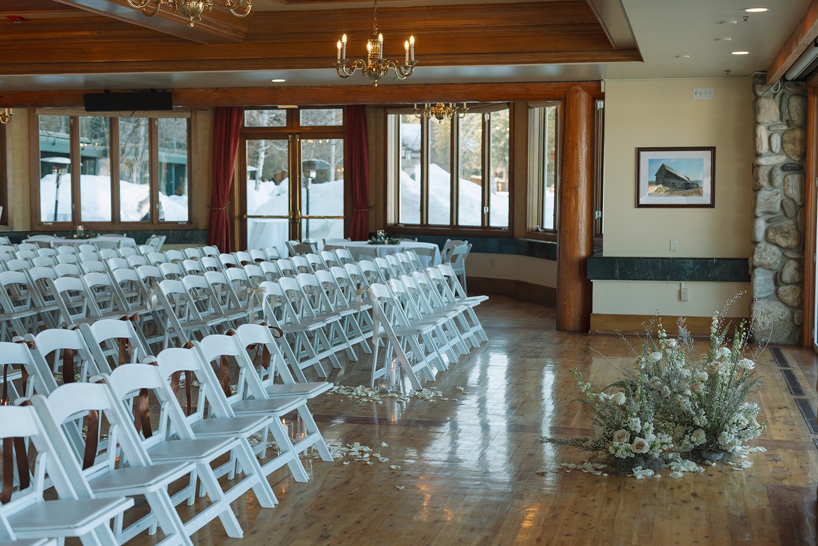 Indoor ceremony with rows of white chairs, candles, and floral aisle arrangements at Shore Lodge spring wedding rocky mountain bride.