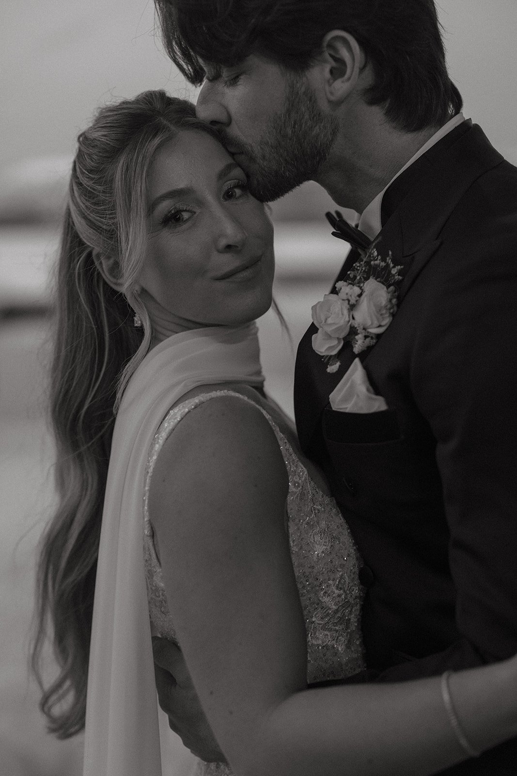 Black and white portrait of groom kissing bride’s forehead during Shore Lodge spring wedding rocky mountain bride.