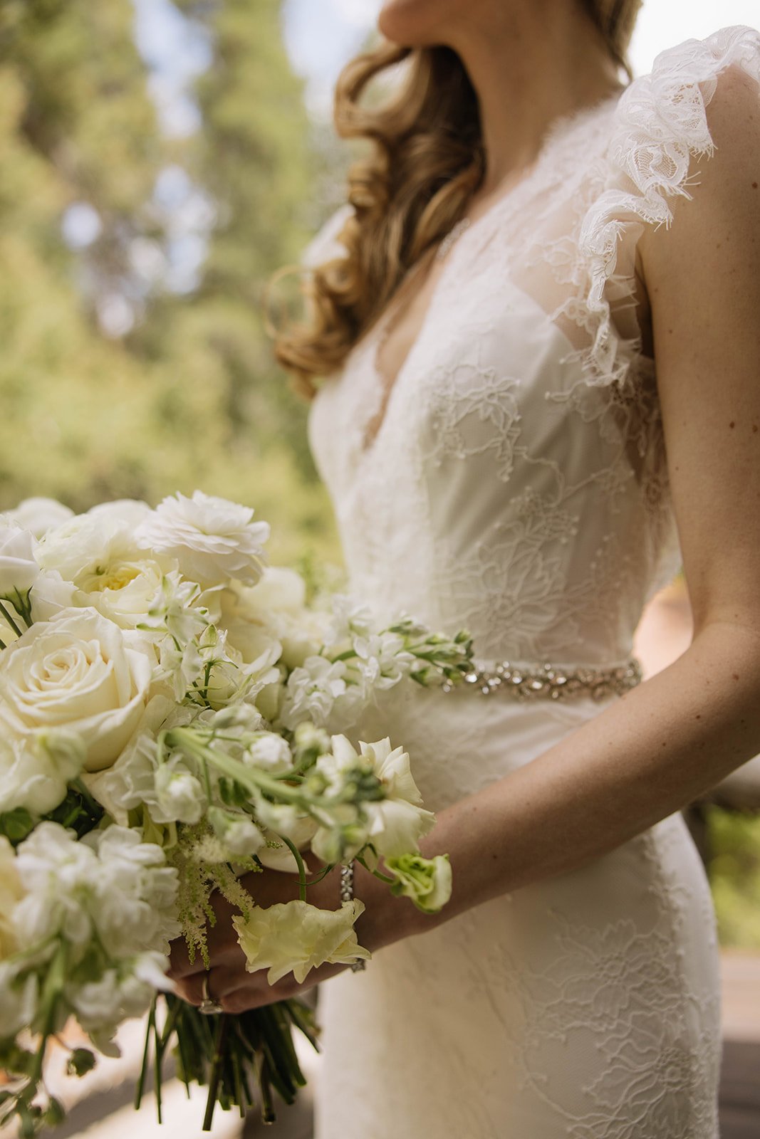 Bride in lace gown holding an elegant white rose and ranunculus bouquet at a Taylor River Lodge wedding with Jillian Brown Photo rocky mountain bride.