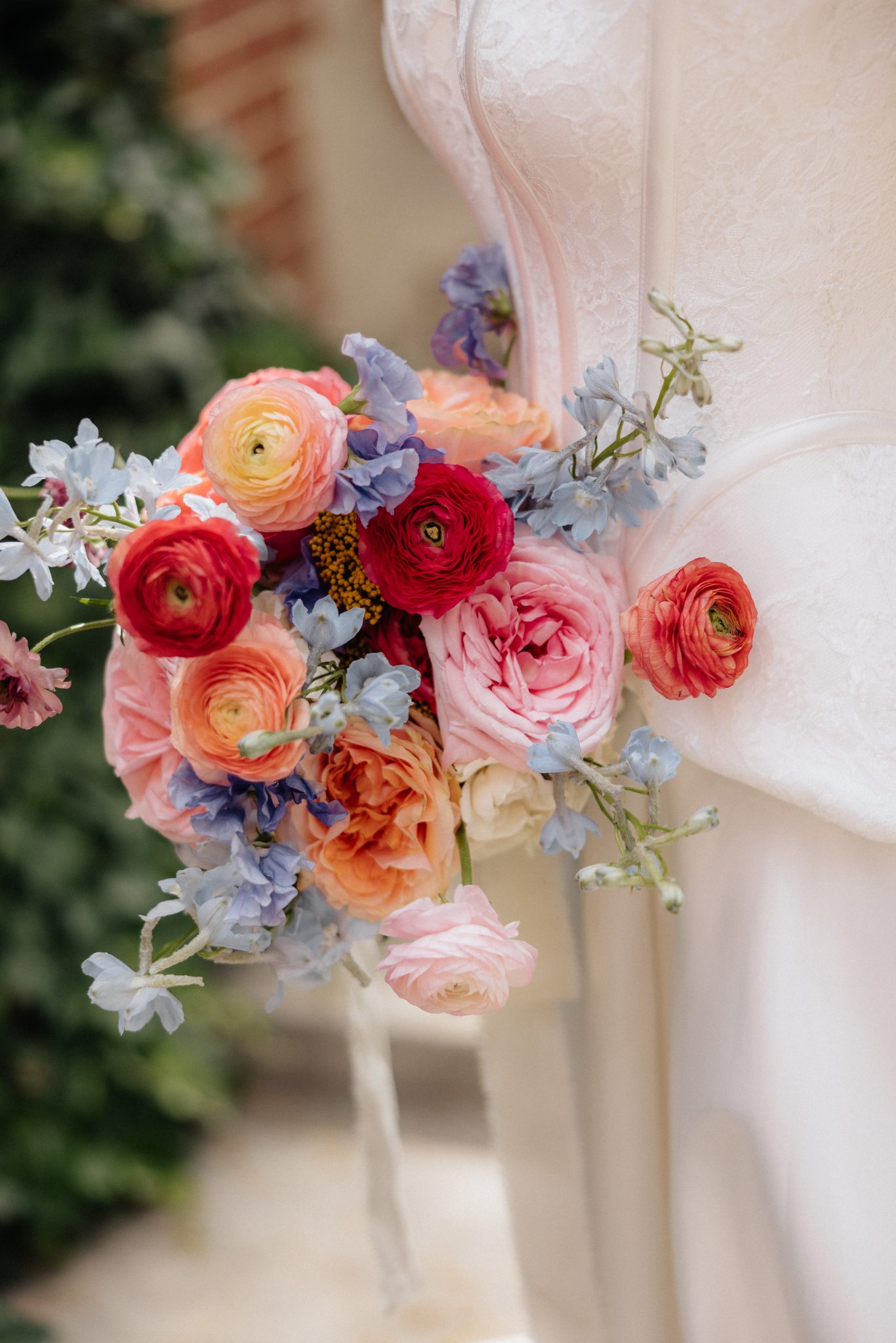 Vibrant bridal bouquet with ranunculus, roses, and pastel blue accents in shades of pink, peach, and red, styled for The Northampton House and Jenny Pearl Photography wedding inspiration rocky mountain bride.