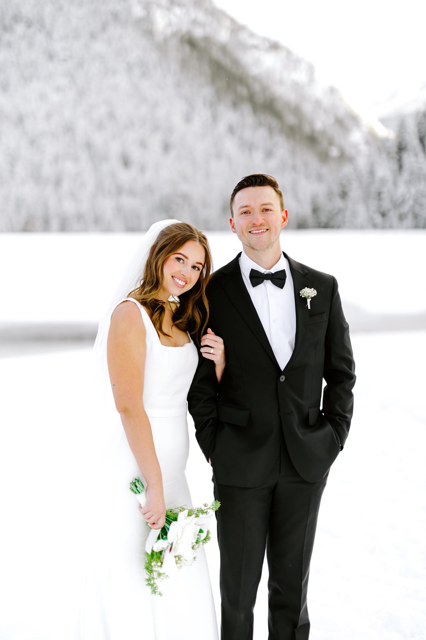 Bride and groom smiling together in the snow with mountain views behind them for Utah wedding bridals rocky mountain bride.