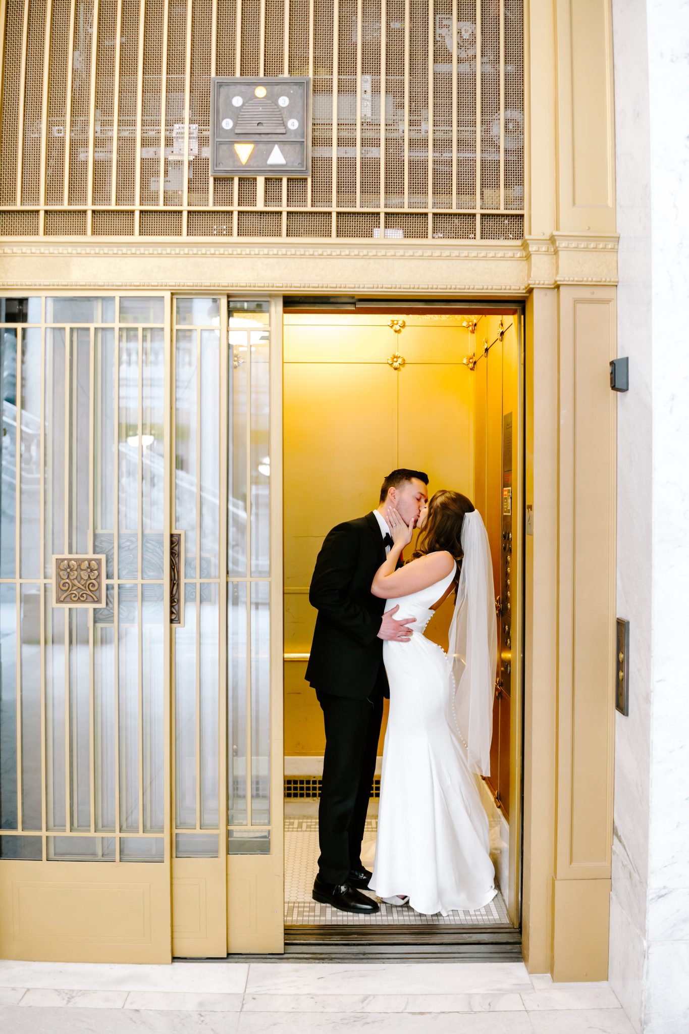 Bride and groom sharing a kiss in a vintage gold elevator during Utah wedding bridals rocky mountain bride.